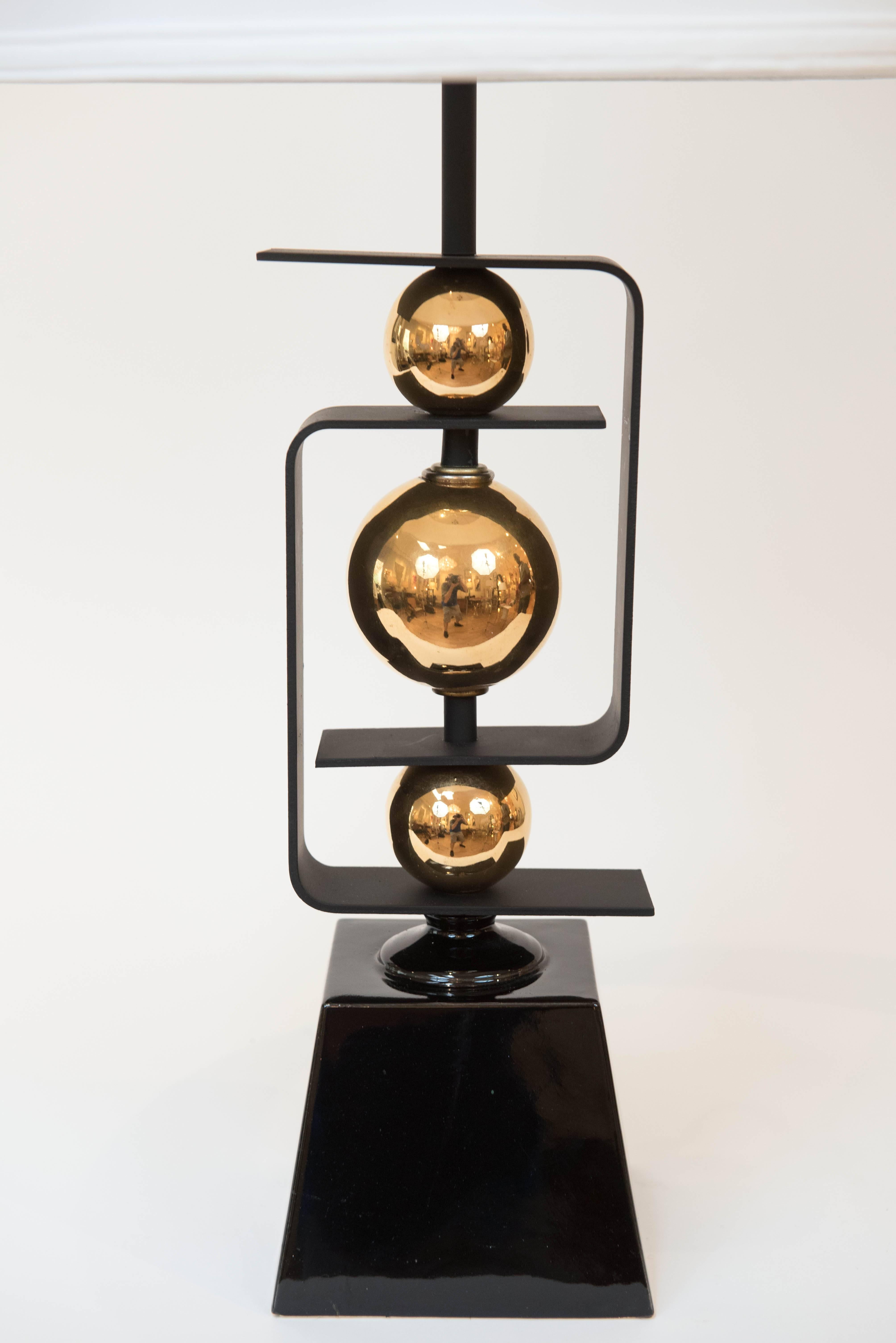 An intriguing and unusual pair of metal framed brass ball lamps with glazed black ceramic bases. Shades are optional. 27