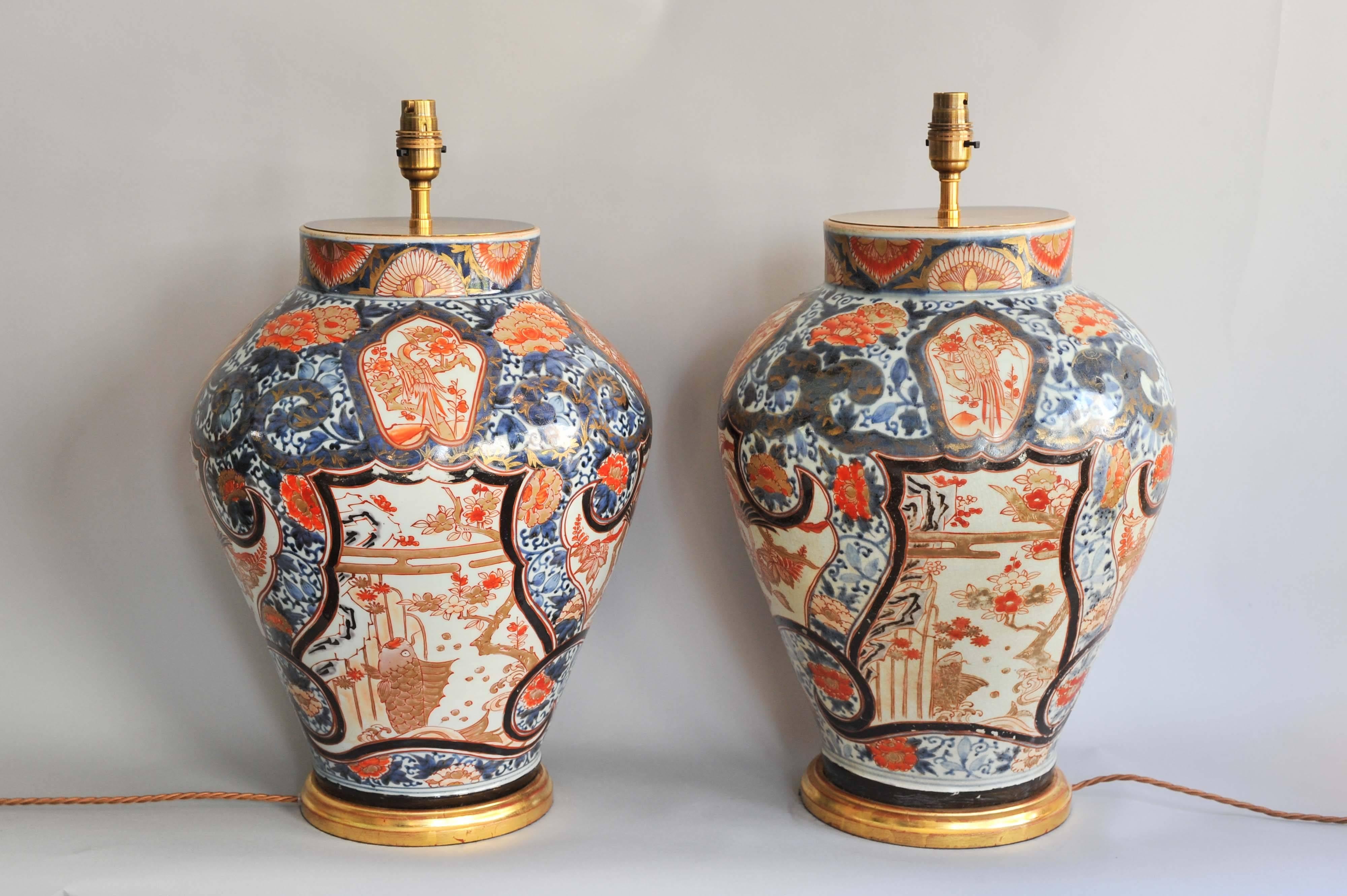 A fine pair of early 18th century Japanese richly decorated imari baluster vases. Lamped on hand-carved and water gilt wooden bases. Both vases have been fitted with antiqued brass plates and adjustable height dual fittings with finals. The vases