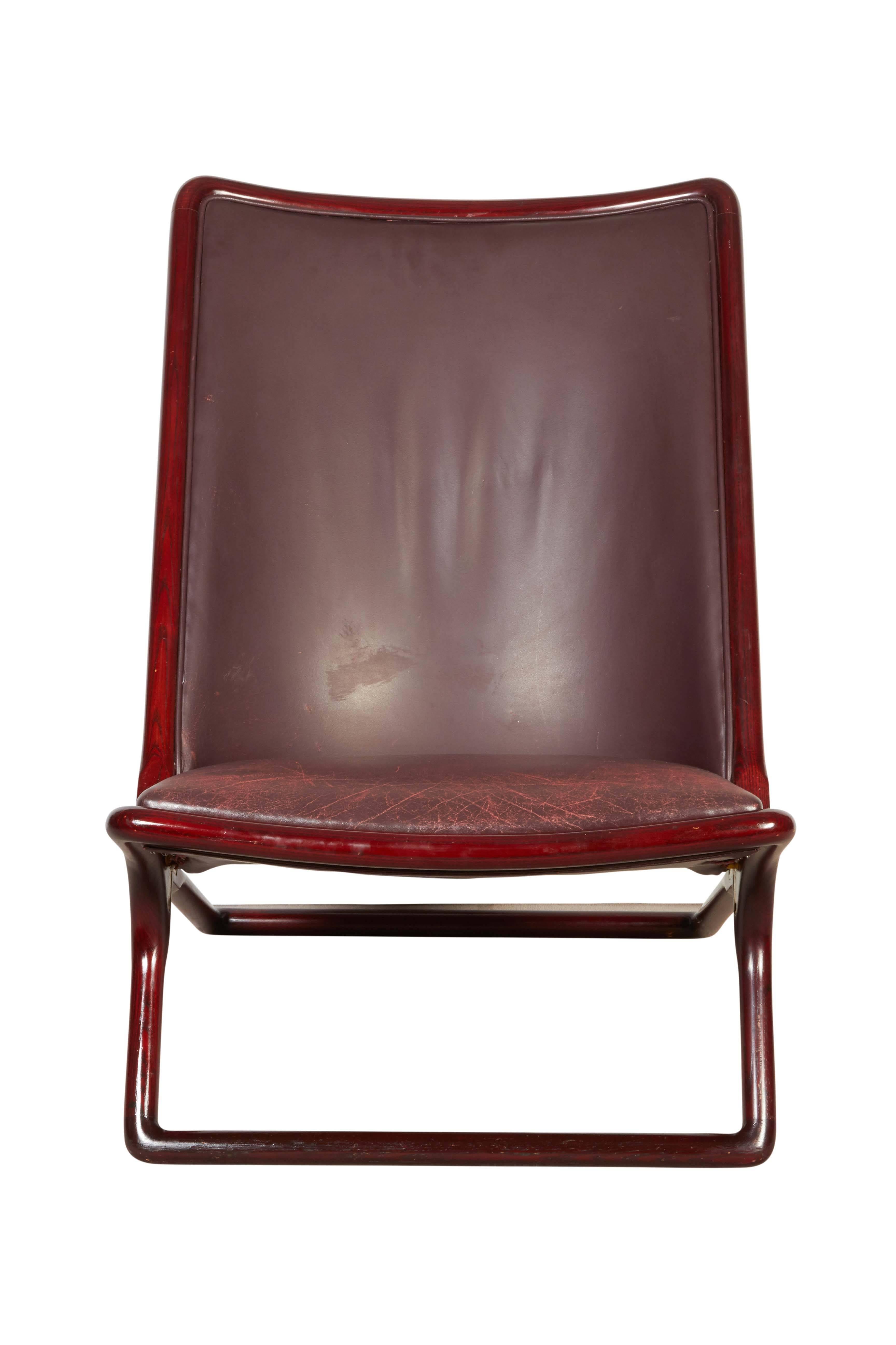A pair of 'Scissor' lounge chairs designed by Ward Bennett for Brickel Associates of Wisconsin, manufactured circa 1970s, each with rich stained wood frames, upholstered in deep burgundy leather with piping. Markings include label [Ward Bennet