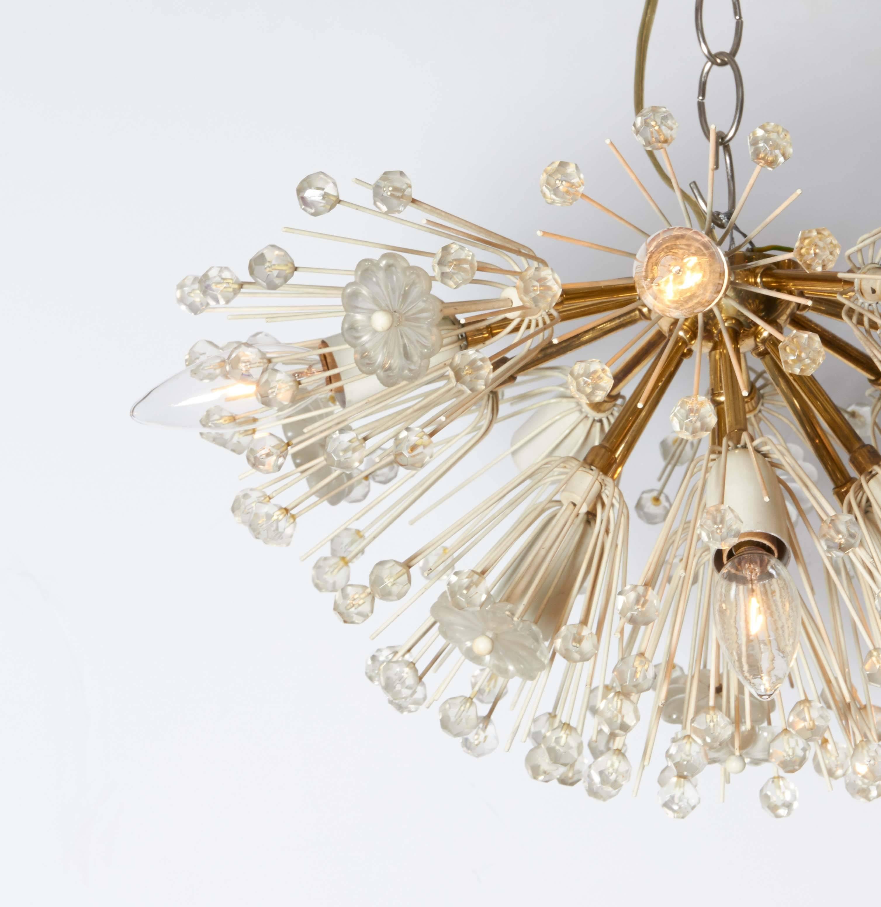 A Sputnik chandelier by Austrian designer Emil Stejnar, manufactured circa 1950s, with brass flush mount nucleus and arms, white enameled socket covers, and surrounding faceted glass beads and rosettes. This light fixture remains in very good