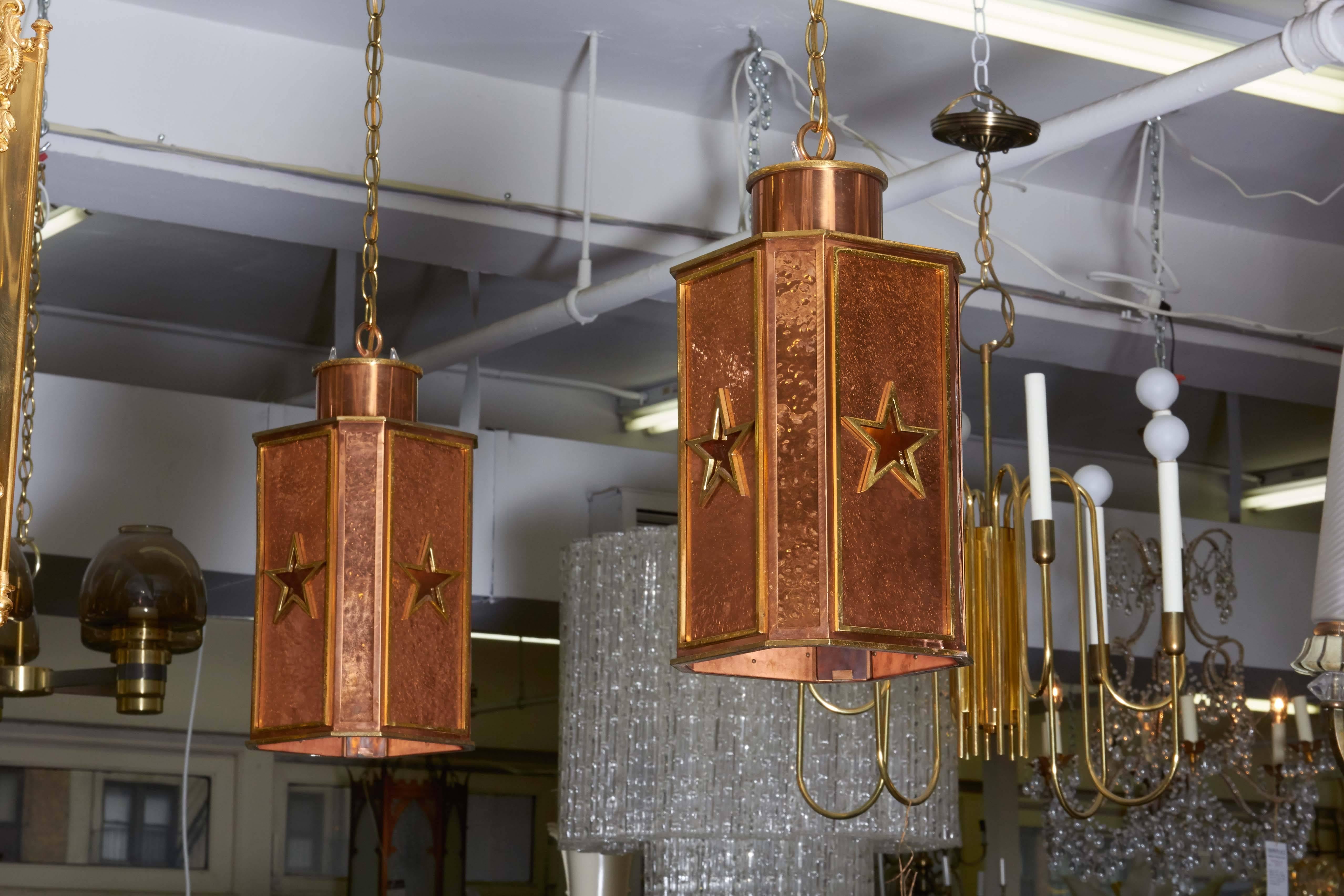 Art Deco era hanging lantern pendants, produced circa 1930s, each in copper, the surface with hammered detail, four sided with brass trimmed star decoration. Wiring and sockets to US standard, each requires five bulbs, one Edison base and four
