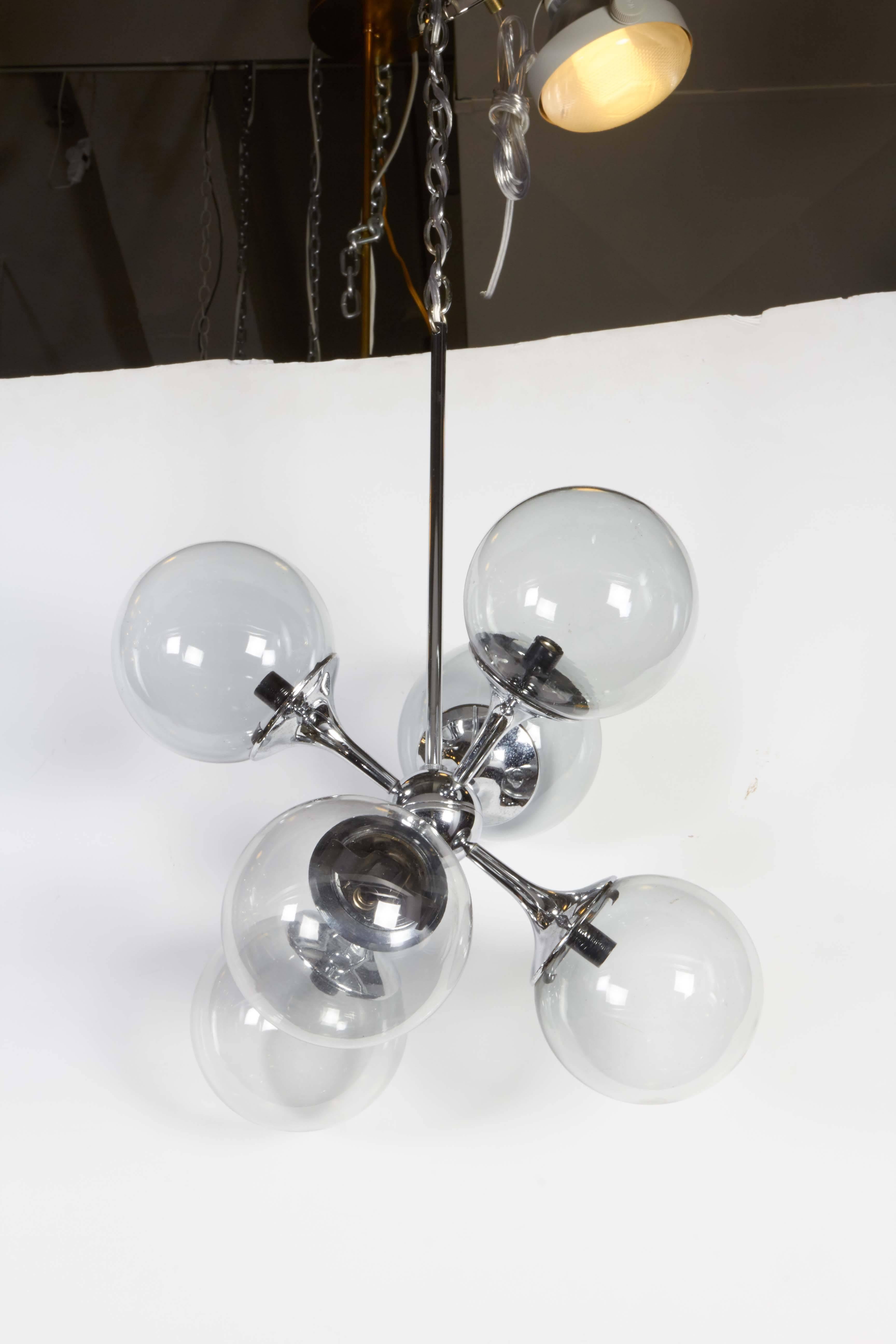 A sputnik chandelier in polished chrome with central nucleus and six tapered arms, each with socket and surrounding smoked glass globe, circa 1970s. This light fixture remains in very good vintage condition, consistent with age and use. 

10564.
 