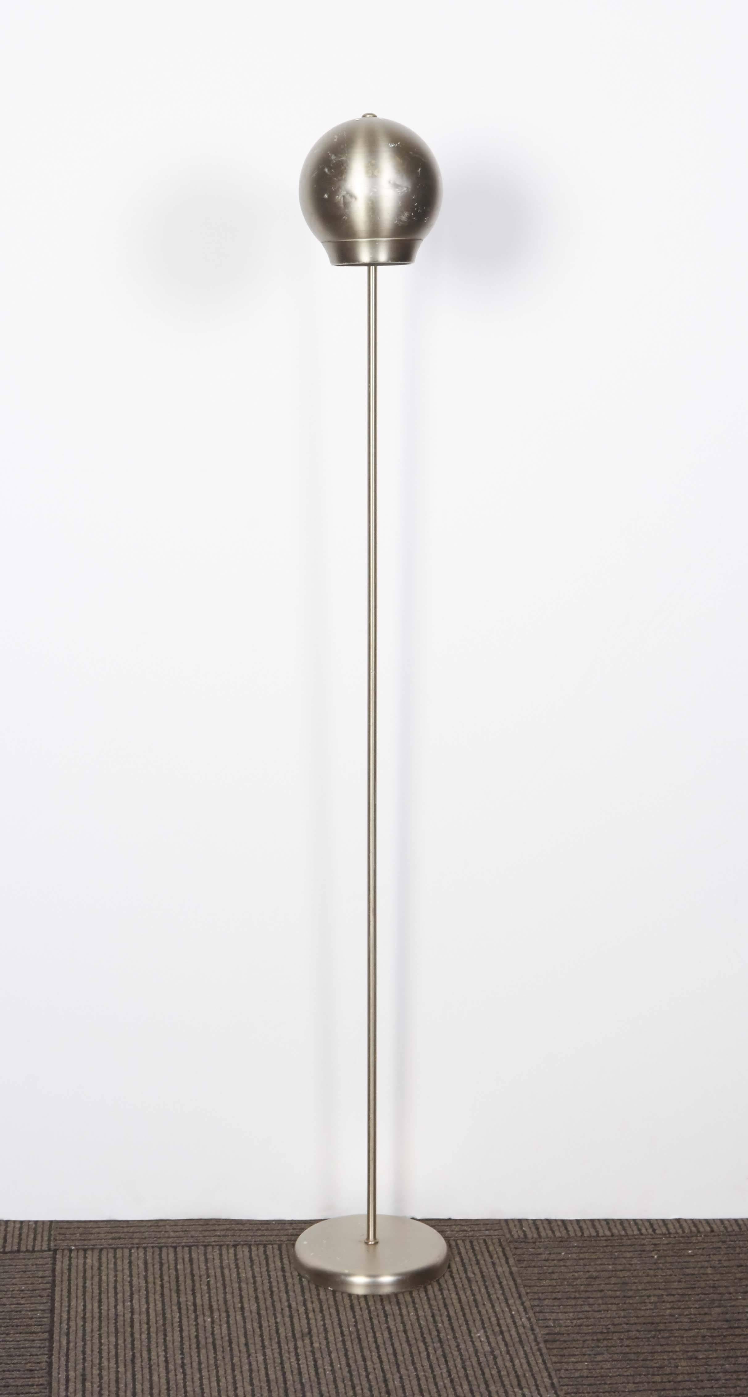 A brushed aluminum floor lamp, evoking the Space Age style, including orb shaped shade with perforated detail, on curved stem and round base. The floor lamp remains in overall good vintage condition, with some presence of wear, including scratches
