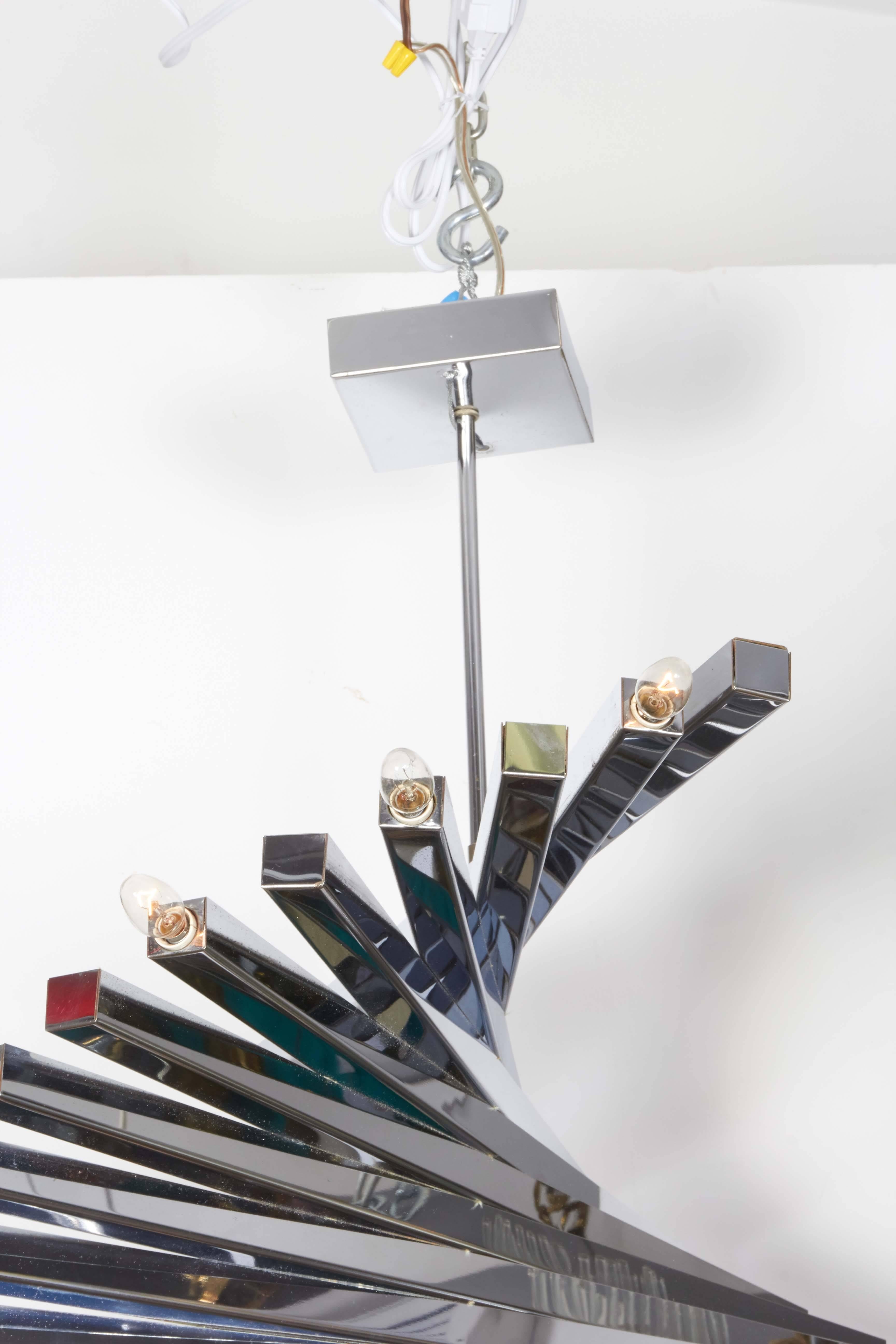 A spiral form circa 1960s chandelier by Italian designer Gaetano Sciolari, comprised of lengthy polished chrome rods, with ten alternating sockets, five to either side, suspended from square ceiling plate. Wiring and sockets to US standard, requires