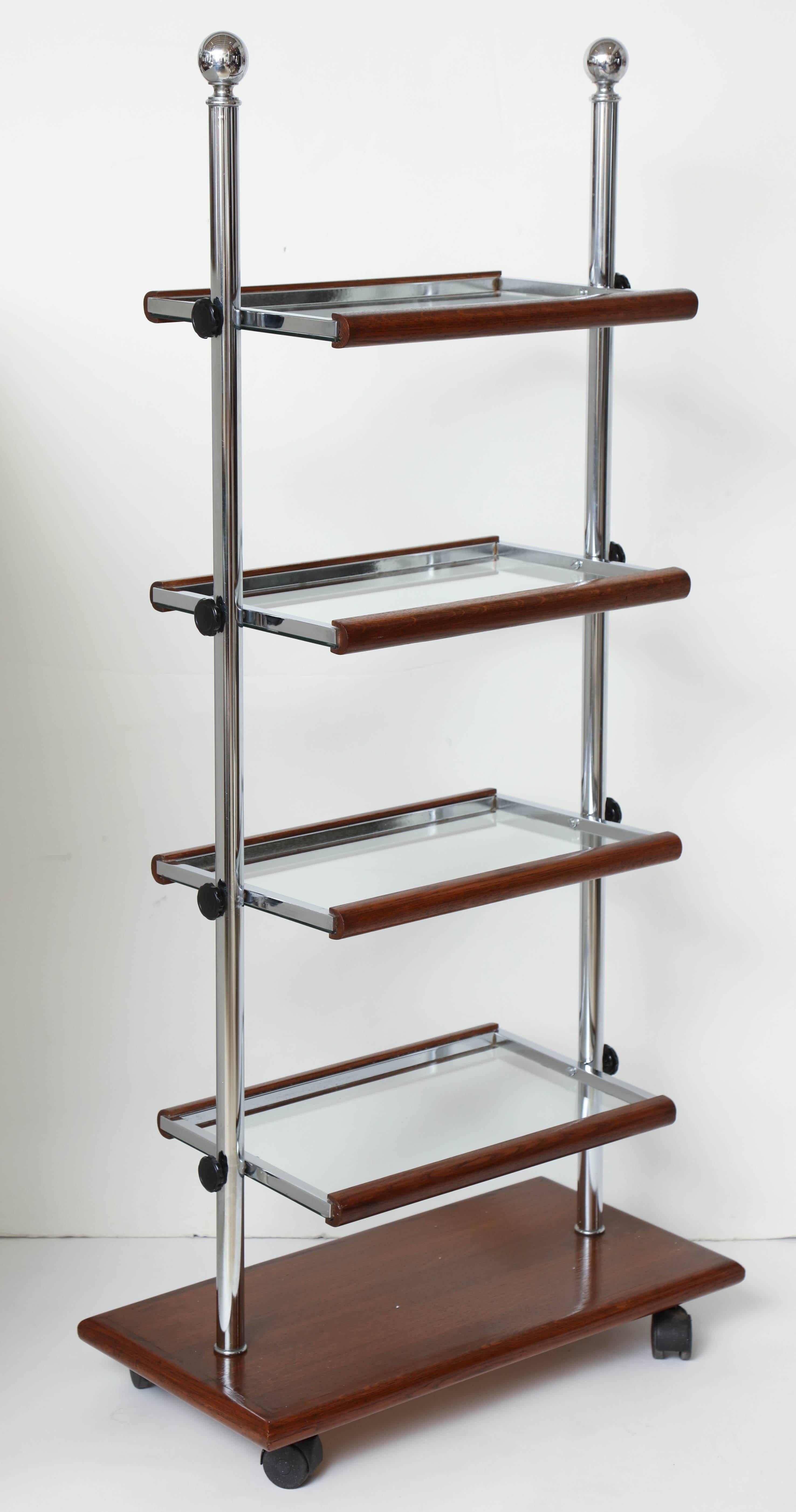 An unusual chrome and oak folding etagere on casters with four adjustable glass shelves, France, circa 1940.

    