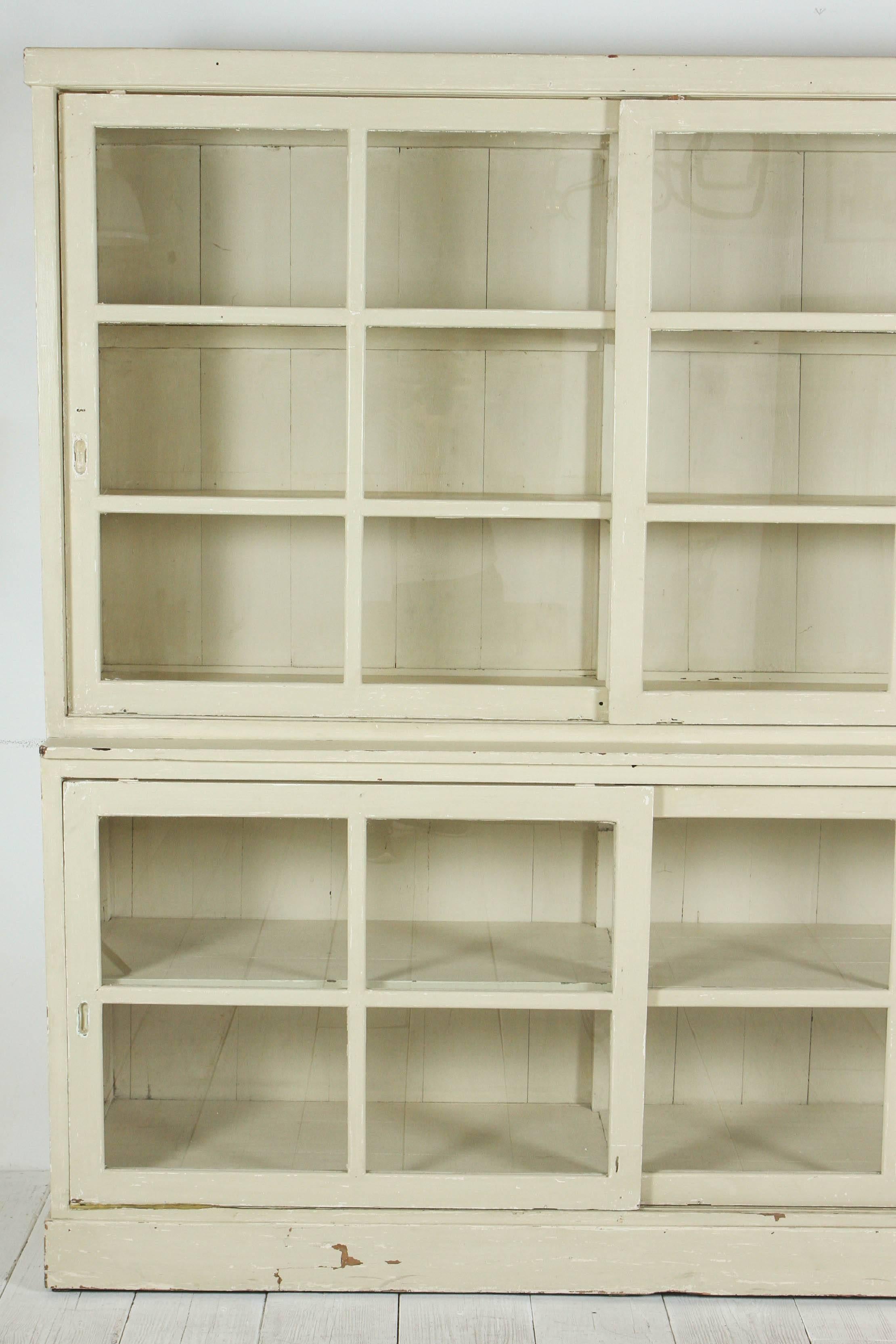 Two part painted cupboard with glass sliding doors and interior shelves.