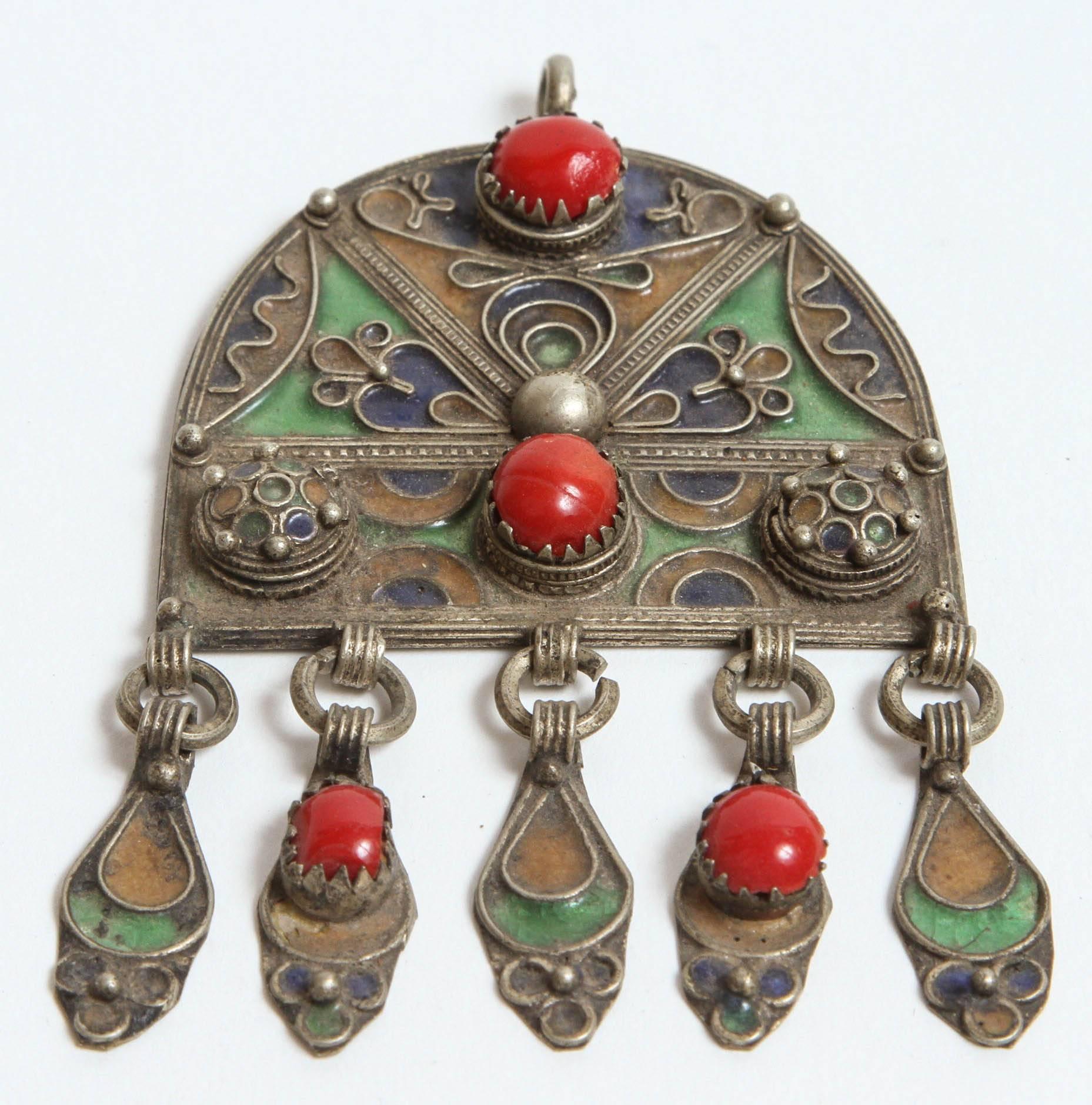 Schöner marokkanischer ethnischer Fibel-Anhänger oder Brosche im Vintage-Stil.
Dieser ethnische marokkanische Silberanhänger ist mit gelb, grün und blau emailliert und mit einem Cabochon aus roten Glasperlen versehen.
In Marokko von den Berberfrauen