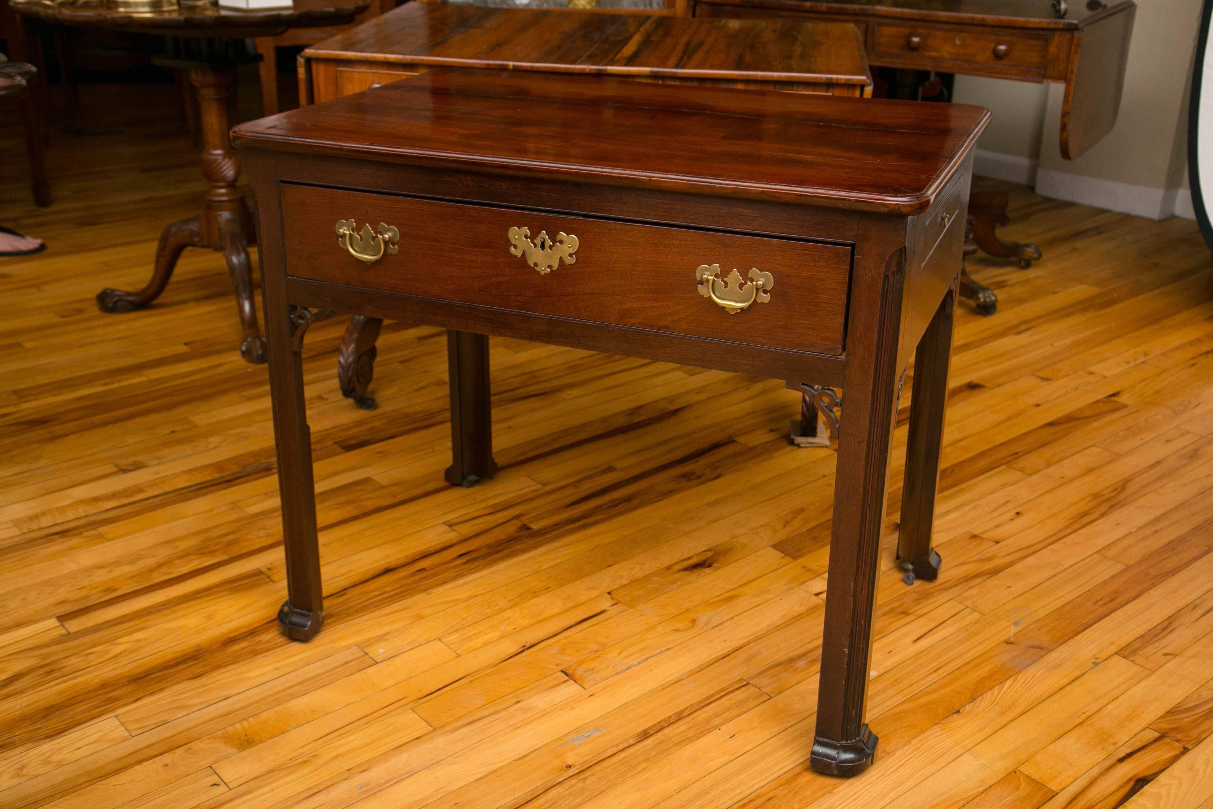 Table d'architecte du XVIIIe siècle avec un seul tiroir qui s'ouvre pour révéler plusieurs compartiments. L'avant de la table est décoré de consoles ouvertes. L'un des côtés de la table est doté d'un tiroir pivotant long et étroit.