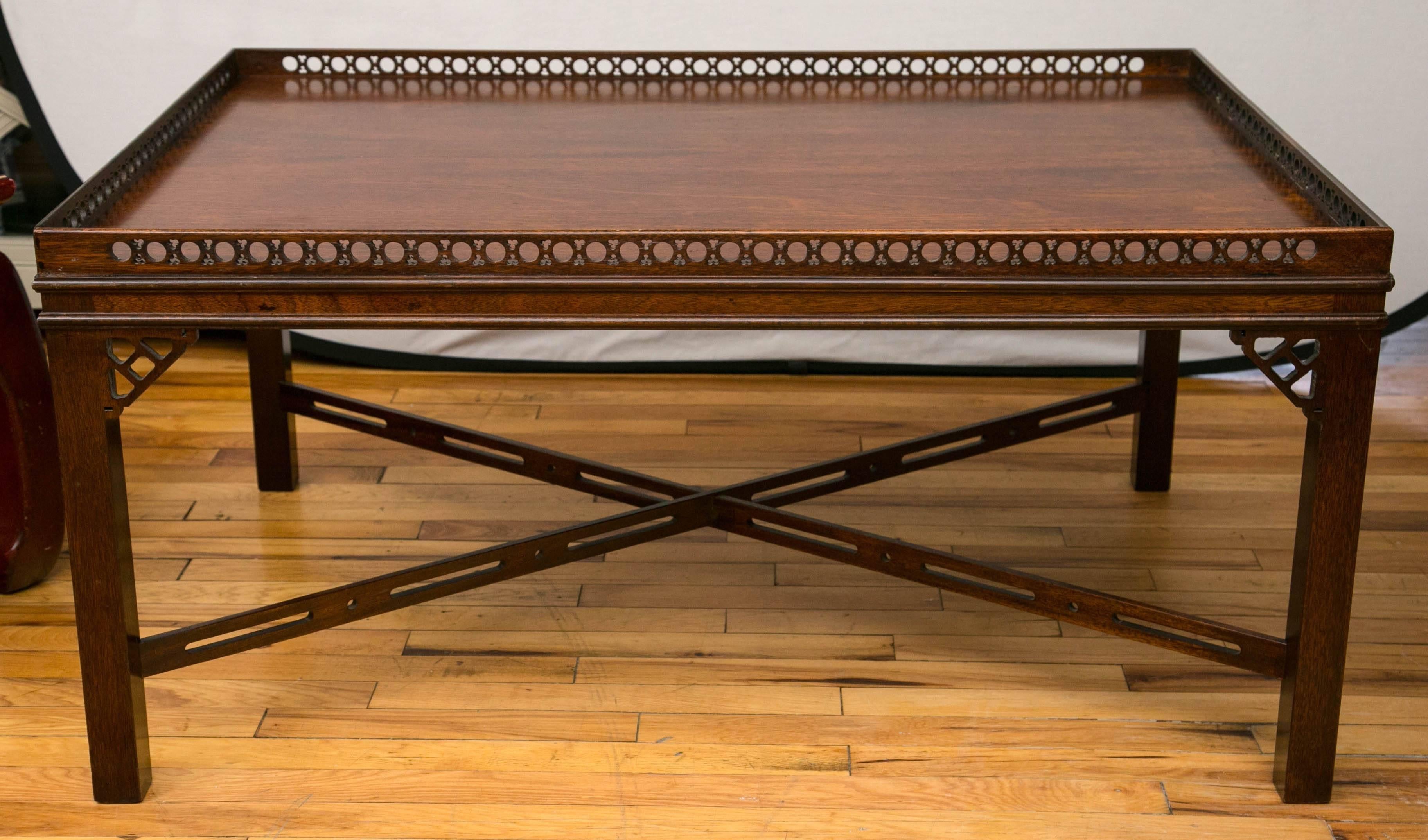 A large rectangular top low table with carved gallery rail supported by four square legs and braced by carved fretwork stretchers. Fretwork corner brackets on top leg joints.
   