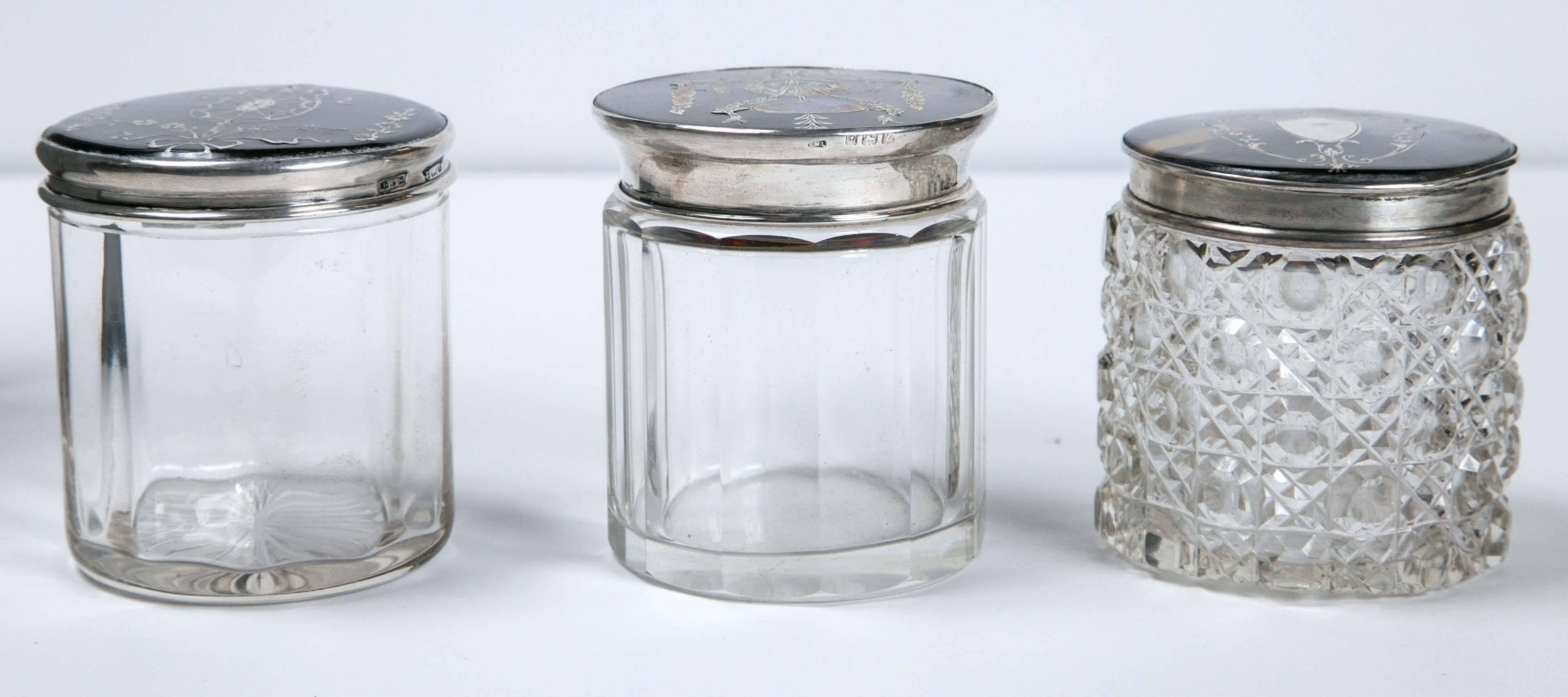 Early 20th century lot of antique dresser jars with tortoise lids and sterling. (1) Dresser jar with shell top and sterling silver inlay, glass jar. (2) Dresser jar with tortoise pique top and sterling silver rim, glass jar. (3) Dresser jar with