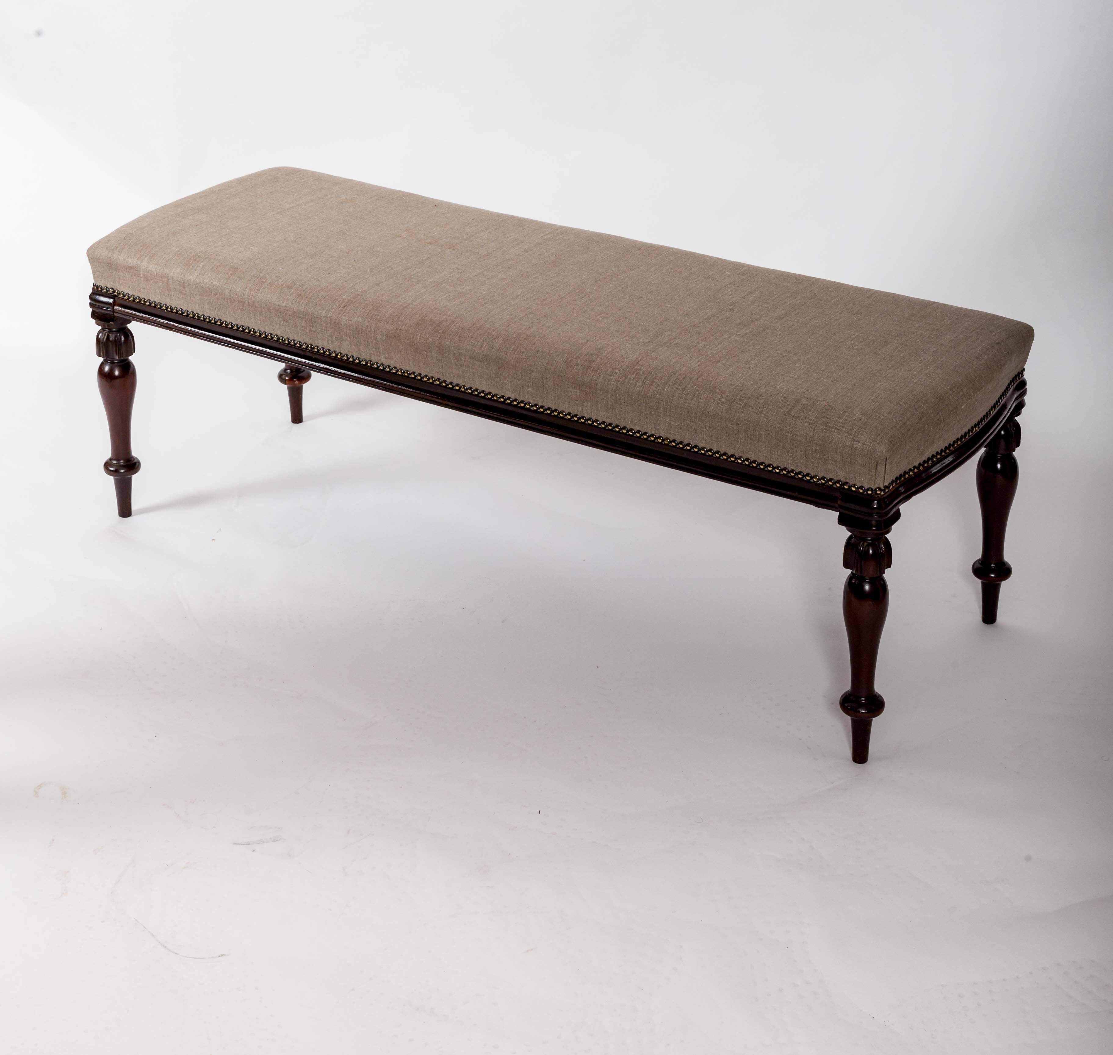Linen upholstered with nailheads, reeded and turned legs. Wooded molded edge. Perfect for the foot of a bed. Measures: 46.5