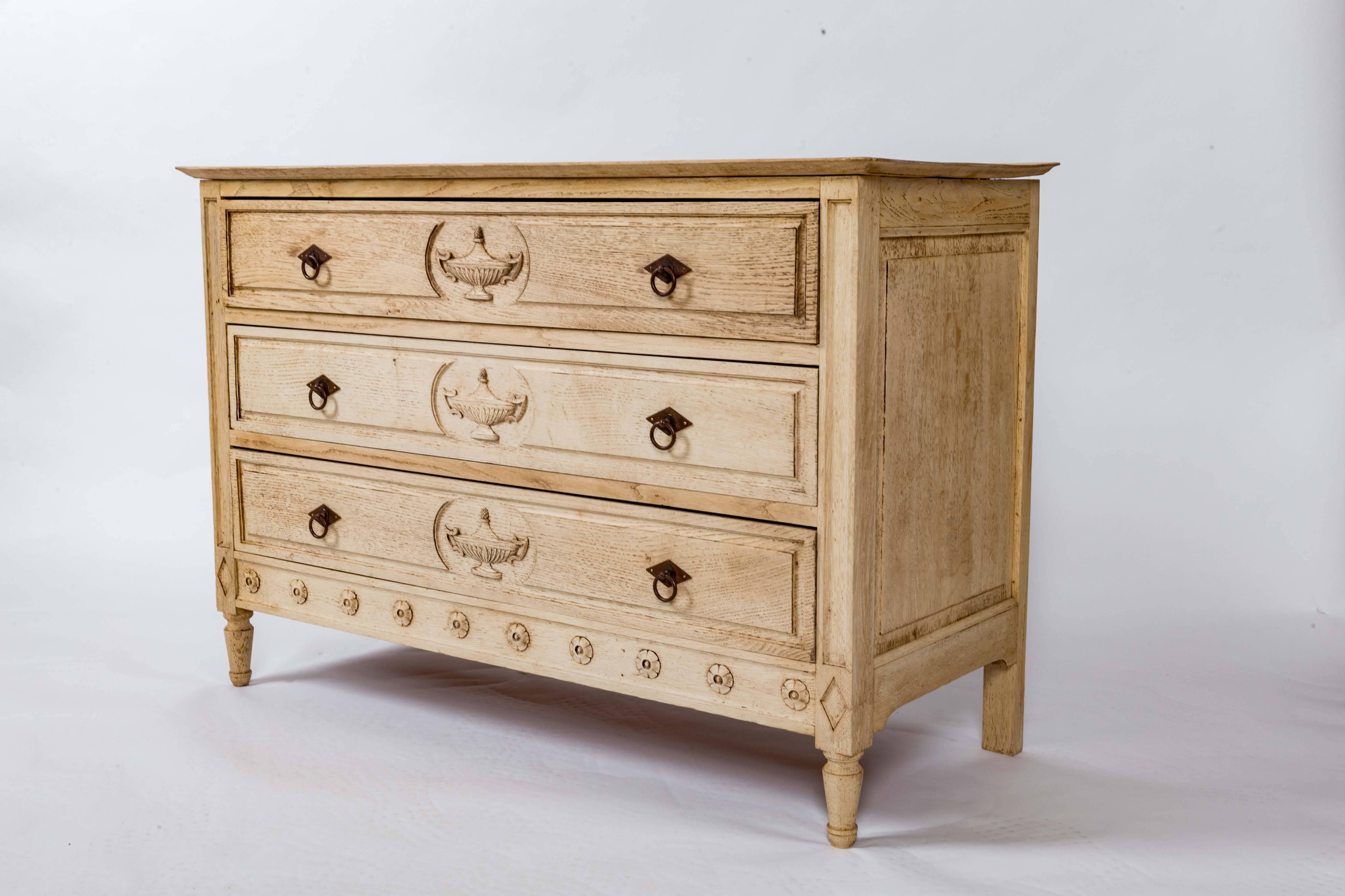 Three-drawers with iron pulls, neoclassical carved urns and carved rosettes on skirt. Fielded panel side and turned feet.