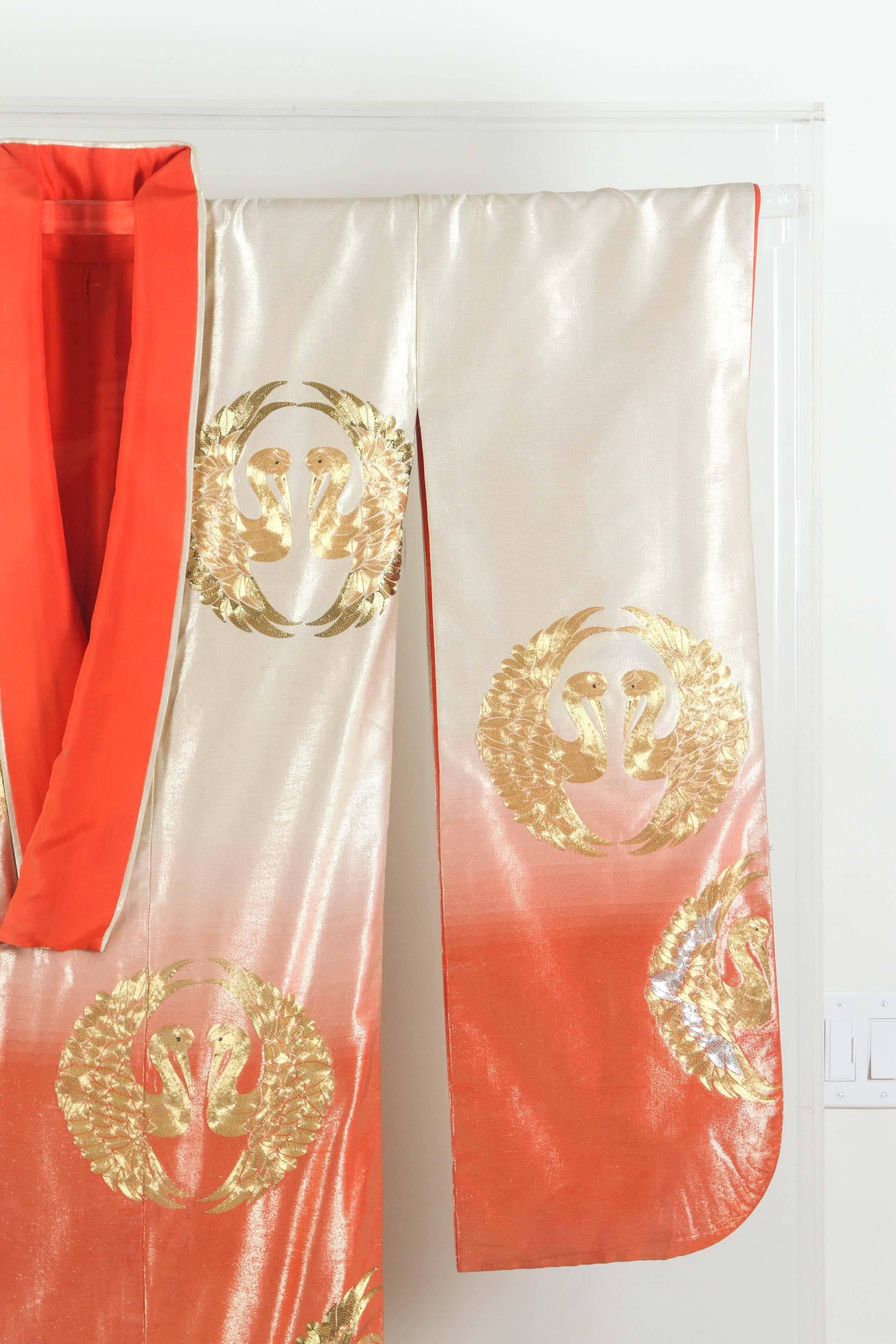 A vintage Japanese ceremonial kimono, circa 1940-1950, beautifully framed and displayed in a Lucite shadow box. 
An handcrafted unusual gold and orange ceremonial piece in pure silk with intricate embroidery work that depicts cranes designs,