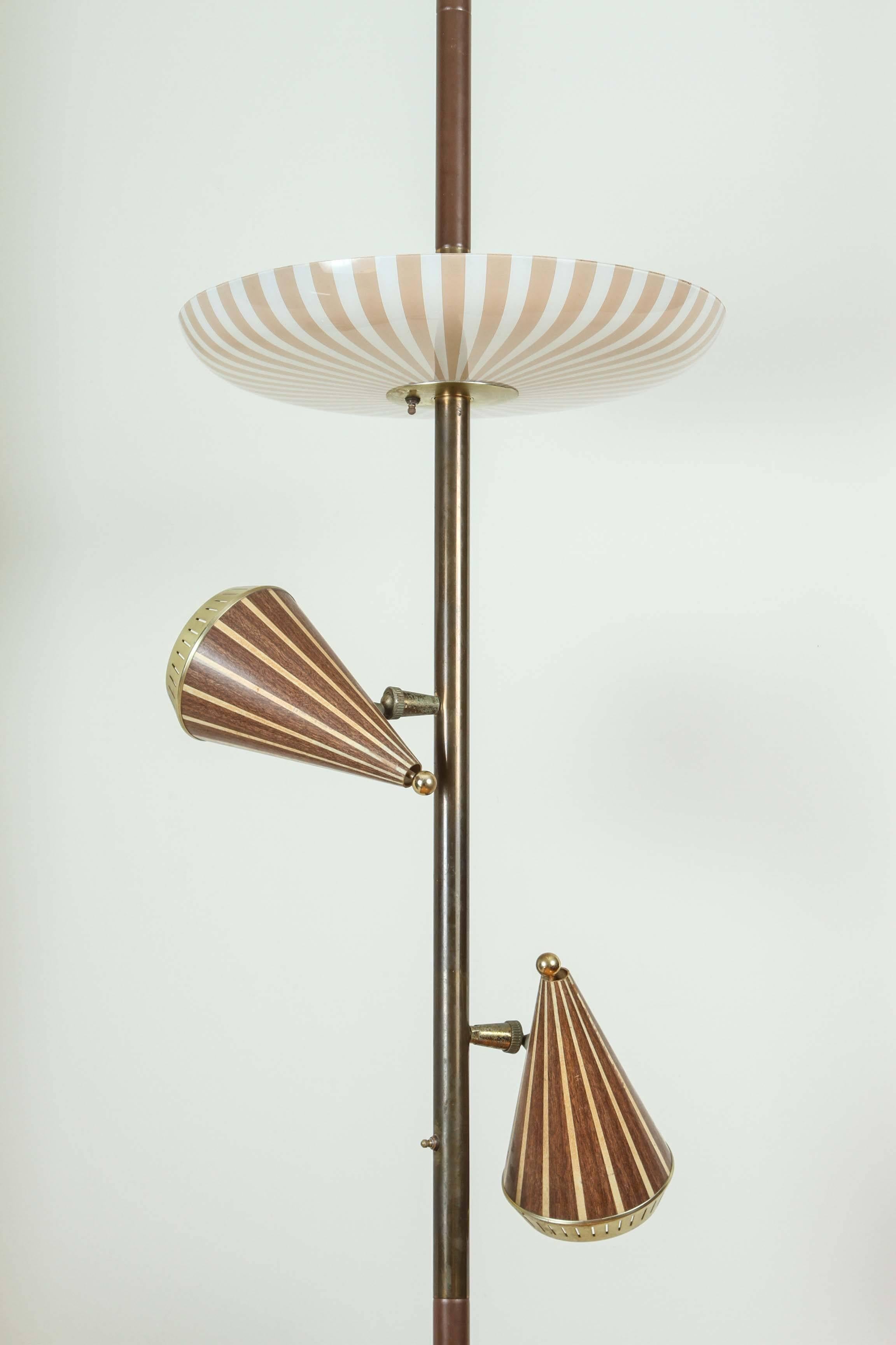 Vintage Mid-Century lamp from the 1950s consists of a large glass plate on top with three lights and two dark inlayed wood patterned sconces that can rotate 360 degrees or angle in or out attached to a metal brass brown tension pole. 
With a single
