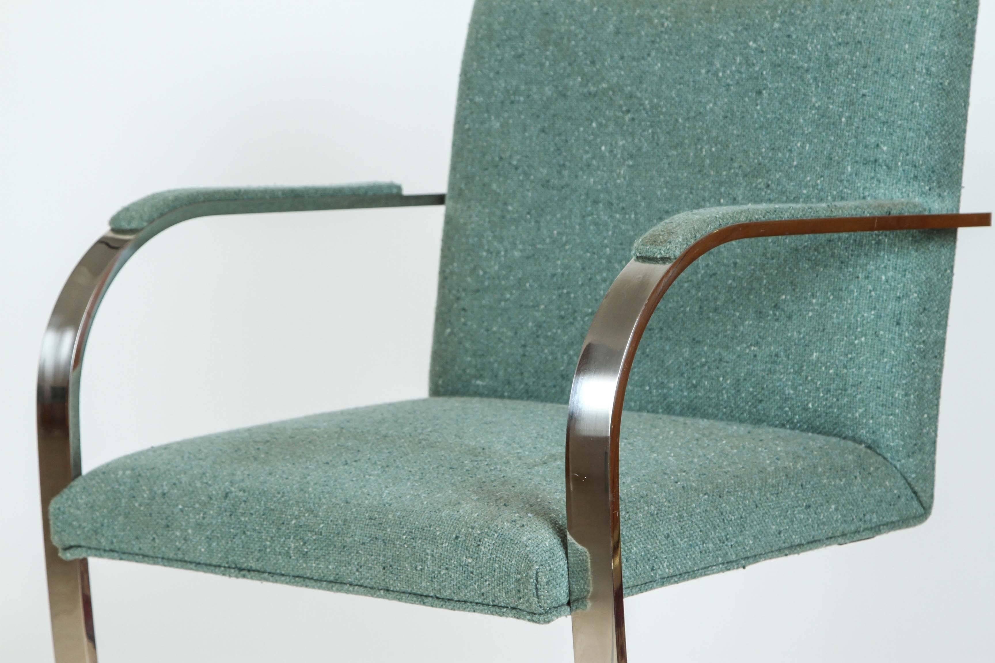Pair of Ludwig Mies Van Der Rohe style flat bar chairs.
Polished flat stainless steel frames upholstered in a Harris wool tweed bluish color over padded seats and backs with a padded armrest for comfort.
Designed by Ludwig Mies van der Rohe and