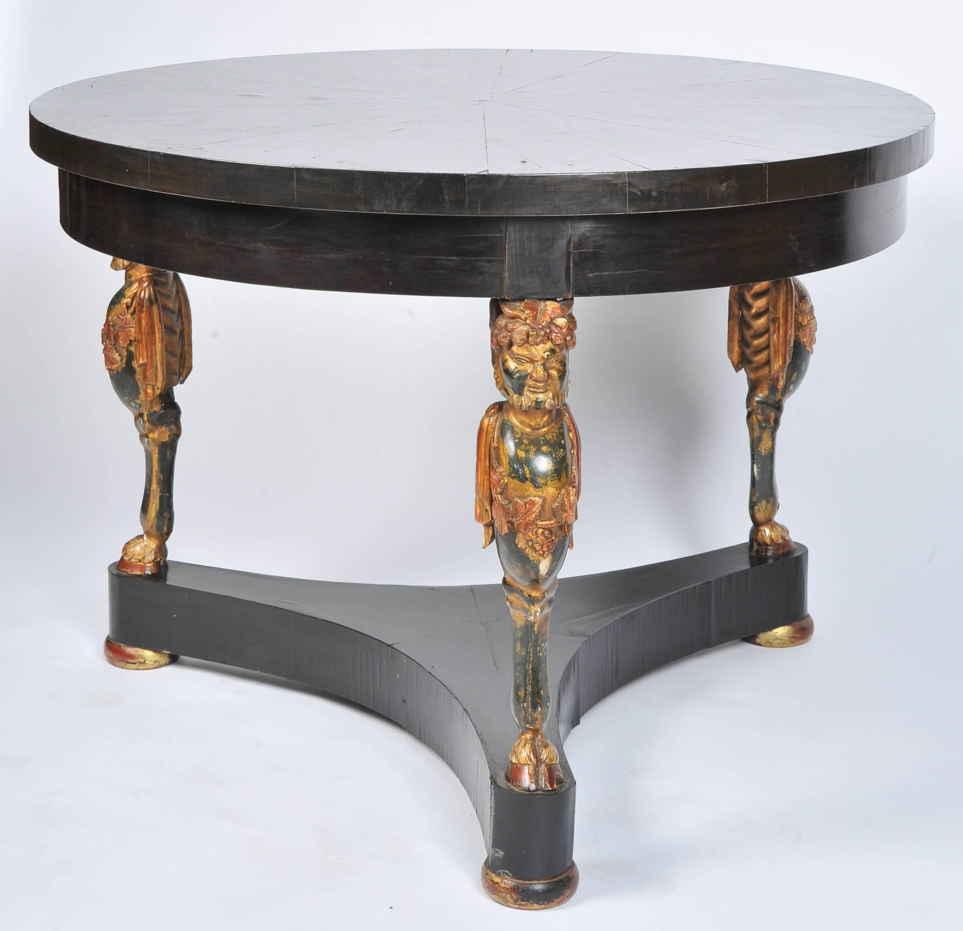 A very striking French early 19th century ebony and carved giltwood gueridon centre table. Having radiating veneers on the table top. Monopodia carved giltwood supports, raised on a triform ebony veneered base.