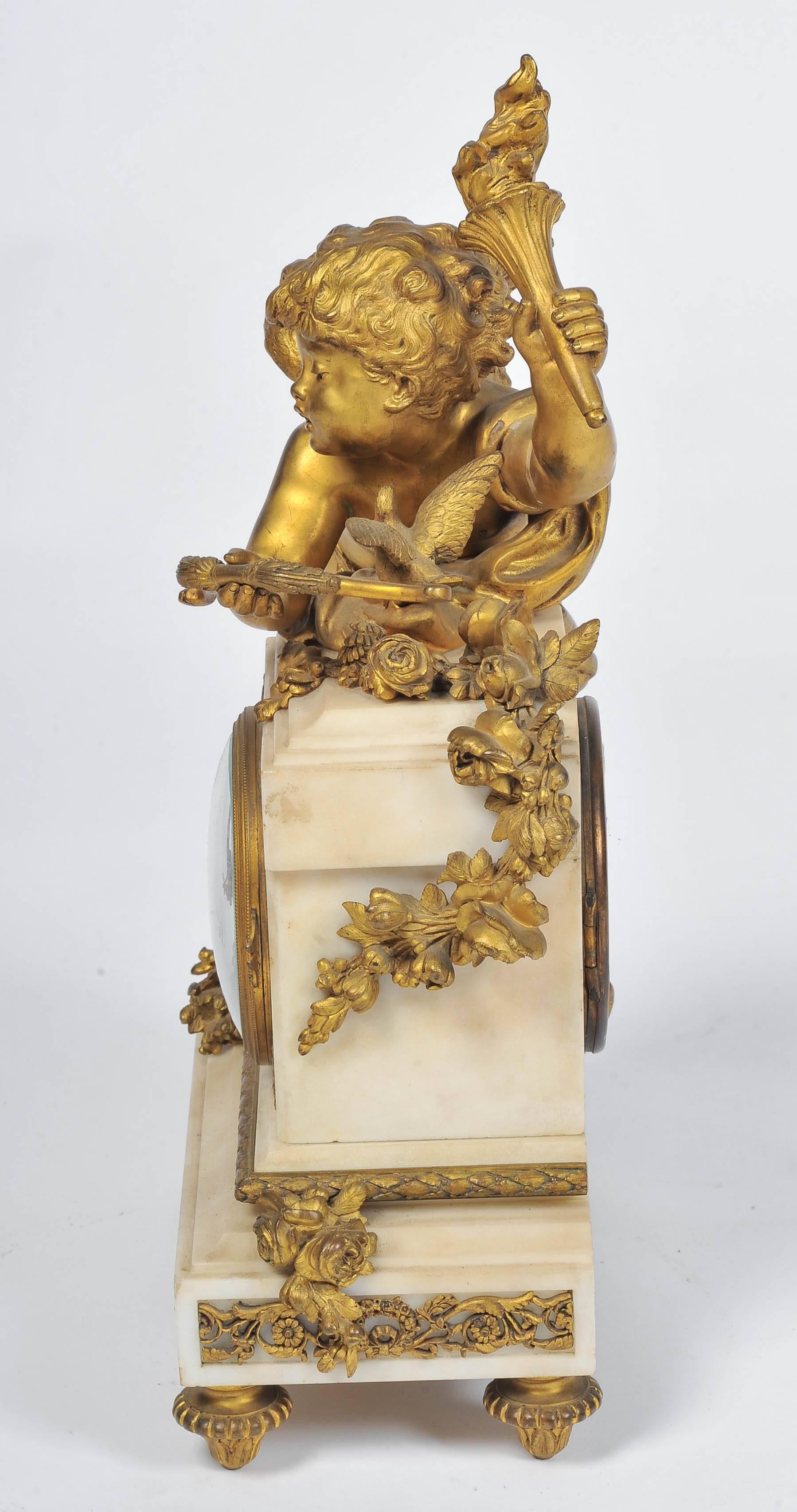 A very pleasing 19th century French gilded ormolu and white marble mantel clock, having a cherub holding a torch and a bow and arrow, leaning against the inset eight day chiming clock.
