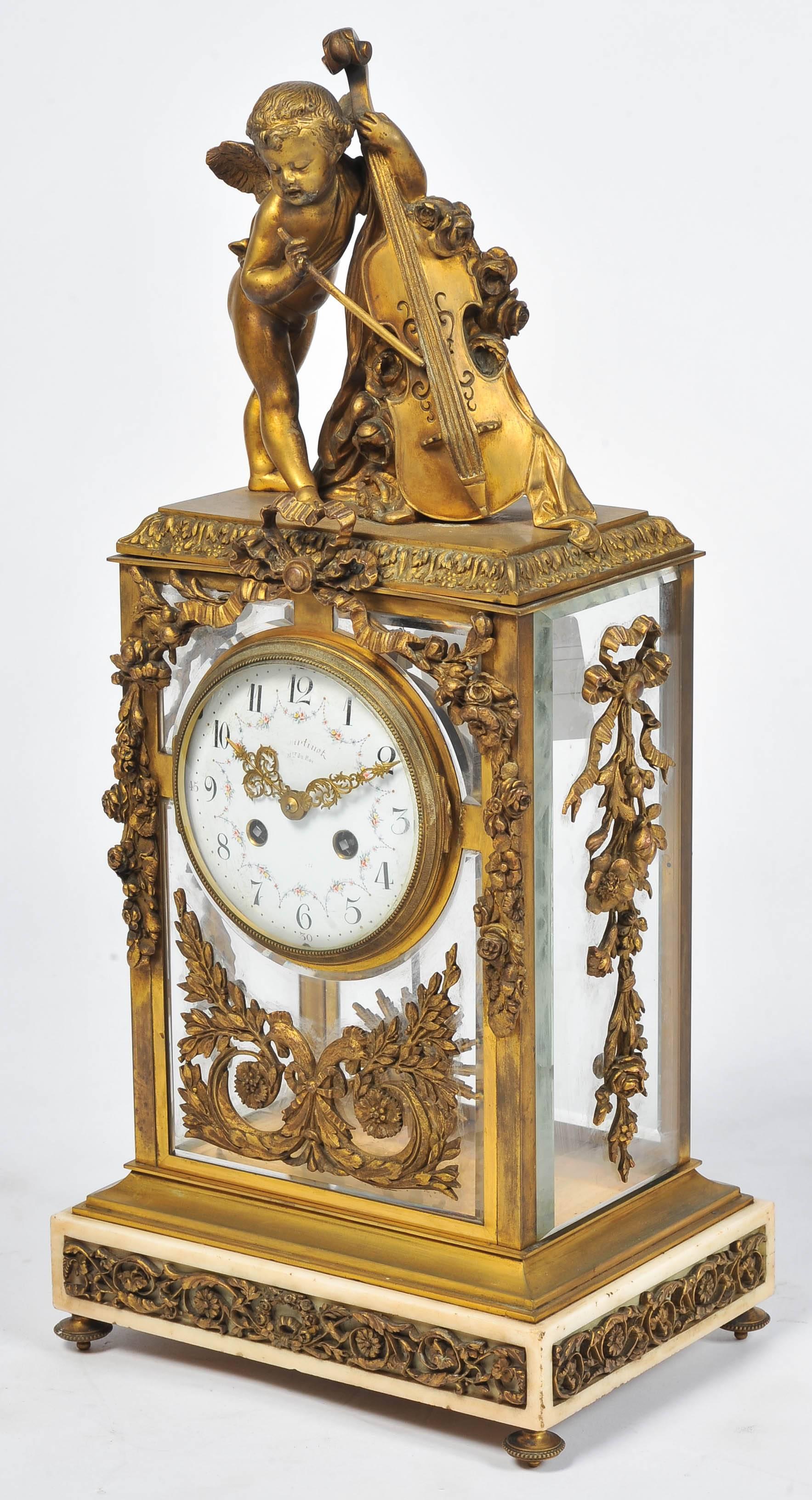 A very good quality 19th Century French gilded ormolu mantel clock. Having a cherub playing a base violin, a four glass case mounted with ormolu foliate and swag decoration, an eight day hour and half hour chiming movement, set on a white marble