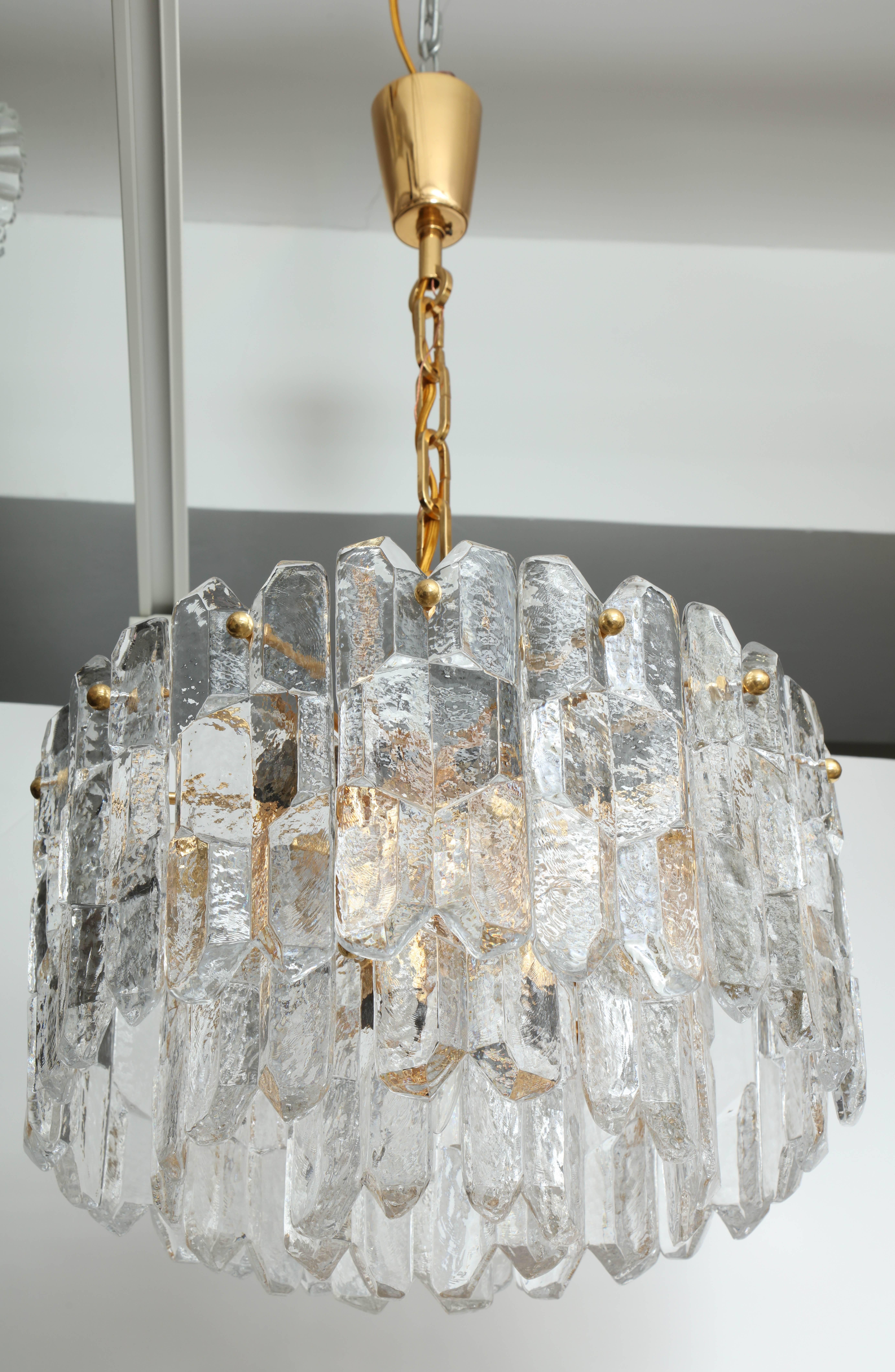 Scandinavian Modern chandelier with layers of chiseled ice glass panels suspended on a 22-karat gilt brass frame. Rewired for use in the USA using gold silk cord. Uses eight chandelier type bulbs. Chandelier body measures 12.5