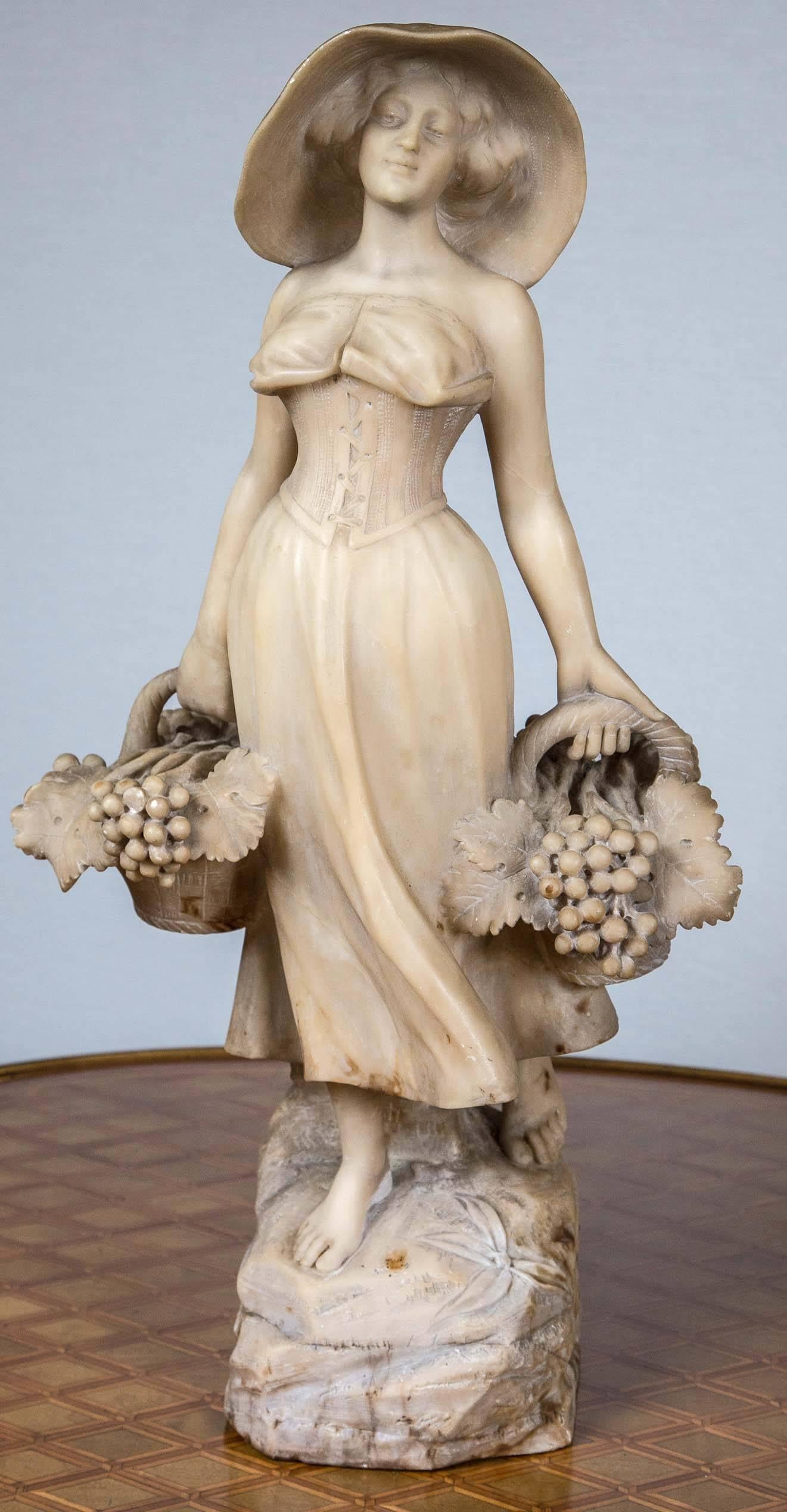 She stands on a rock grouping with a basket of grapes and grape leaves in each hand.
Her straw had finely carved showing the tight pattern of the straw. She wears a laced bodice and long flowing skirt.
Hand chisel marks evident.
There is no