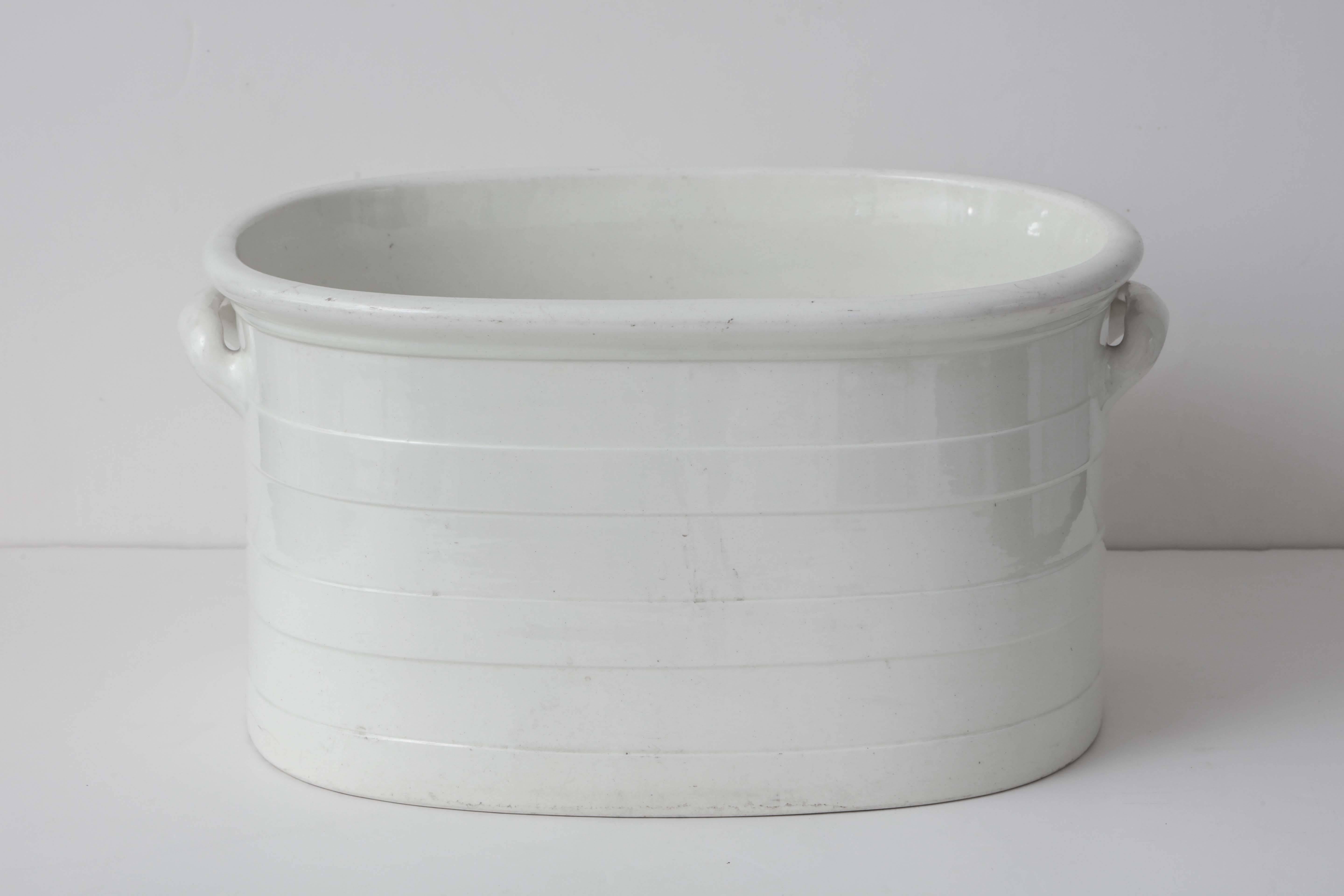 A 19th century English creamware footbath with ribbed decoration and integral handles, stamped Wedgwood.