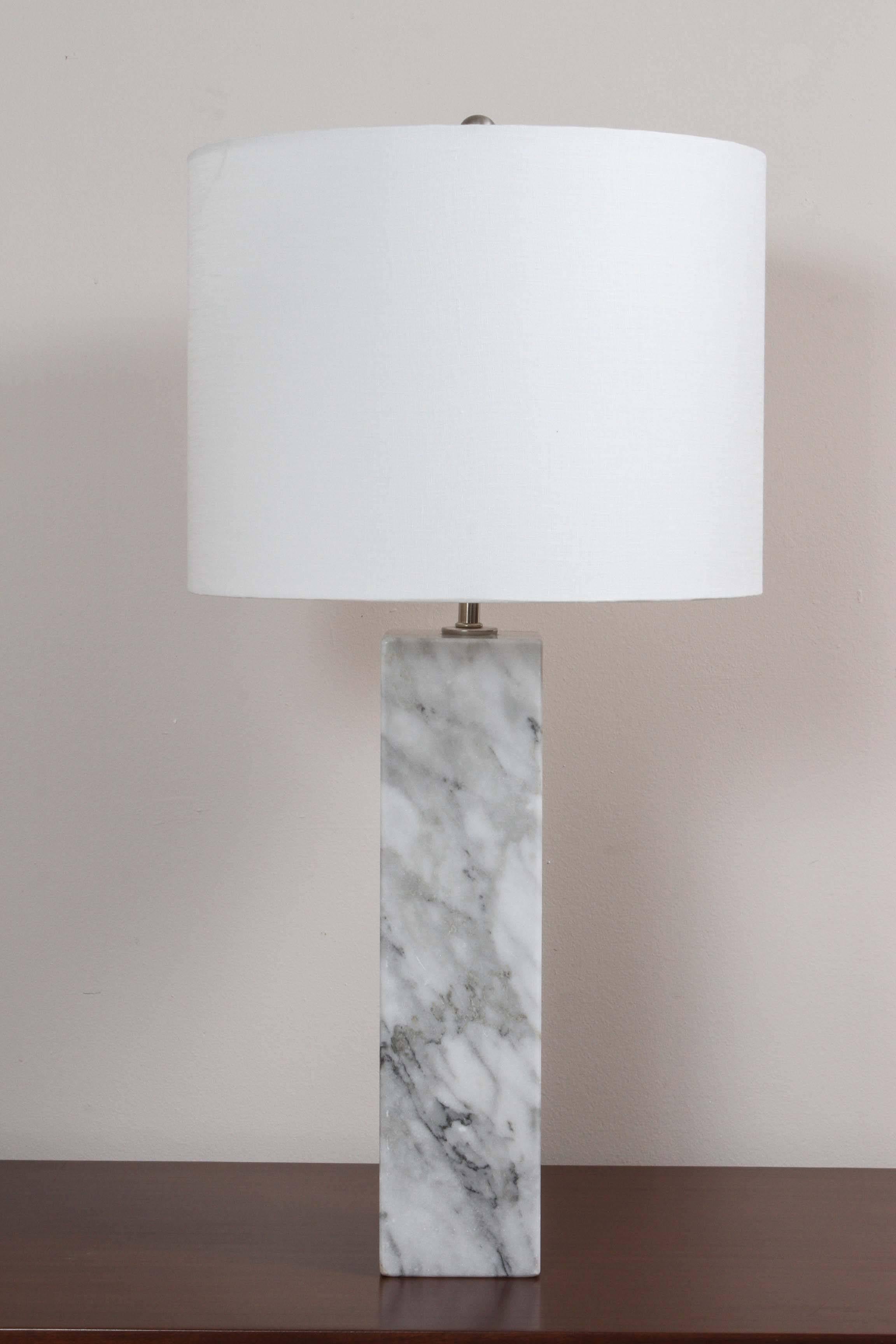 Pair of 1960s Carrera marble table lamps. The lamps are stately and solid/heavy. The drum shade is linen and new. Markings on the marble are beautifully appointed. 