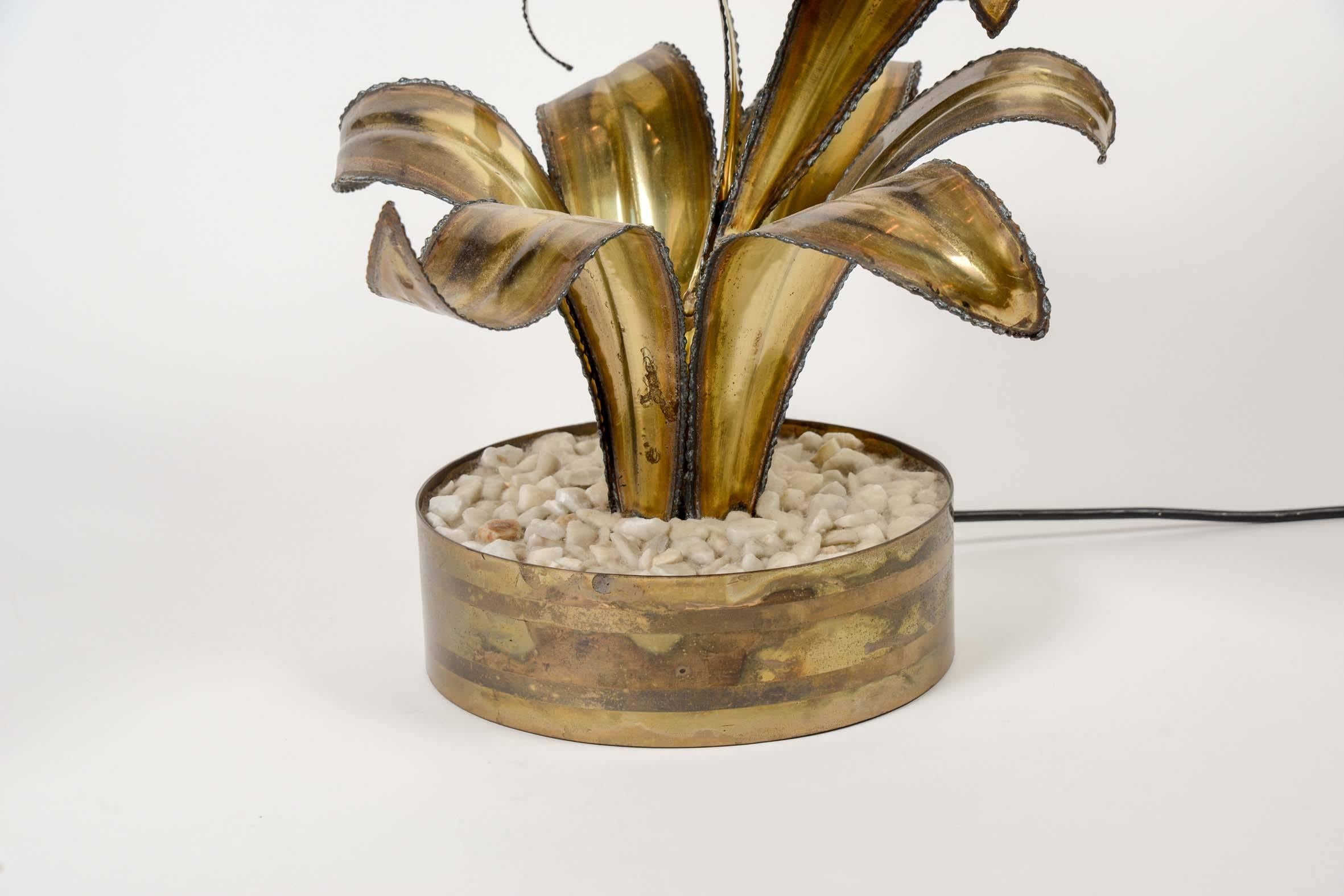 Paire de lampes de table représentant des fleurs avec leurs pétales et leur feuille dans un pot rempli de gravier blanc.

Une source de lumière par lampe.