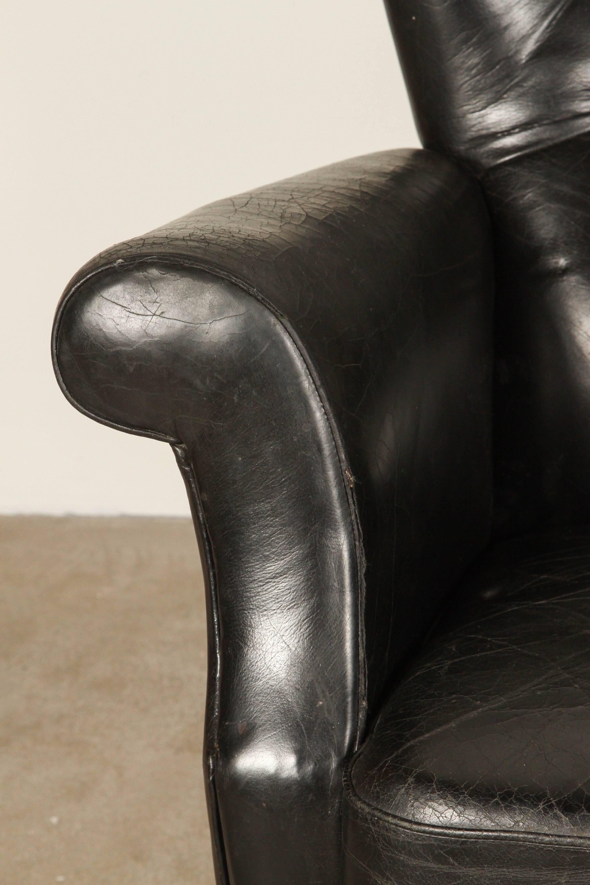 Finn Juhl, black leather armchair with teak base and tapered legs.