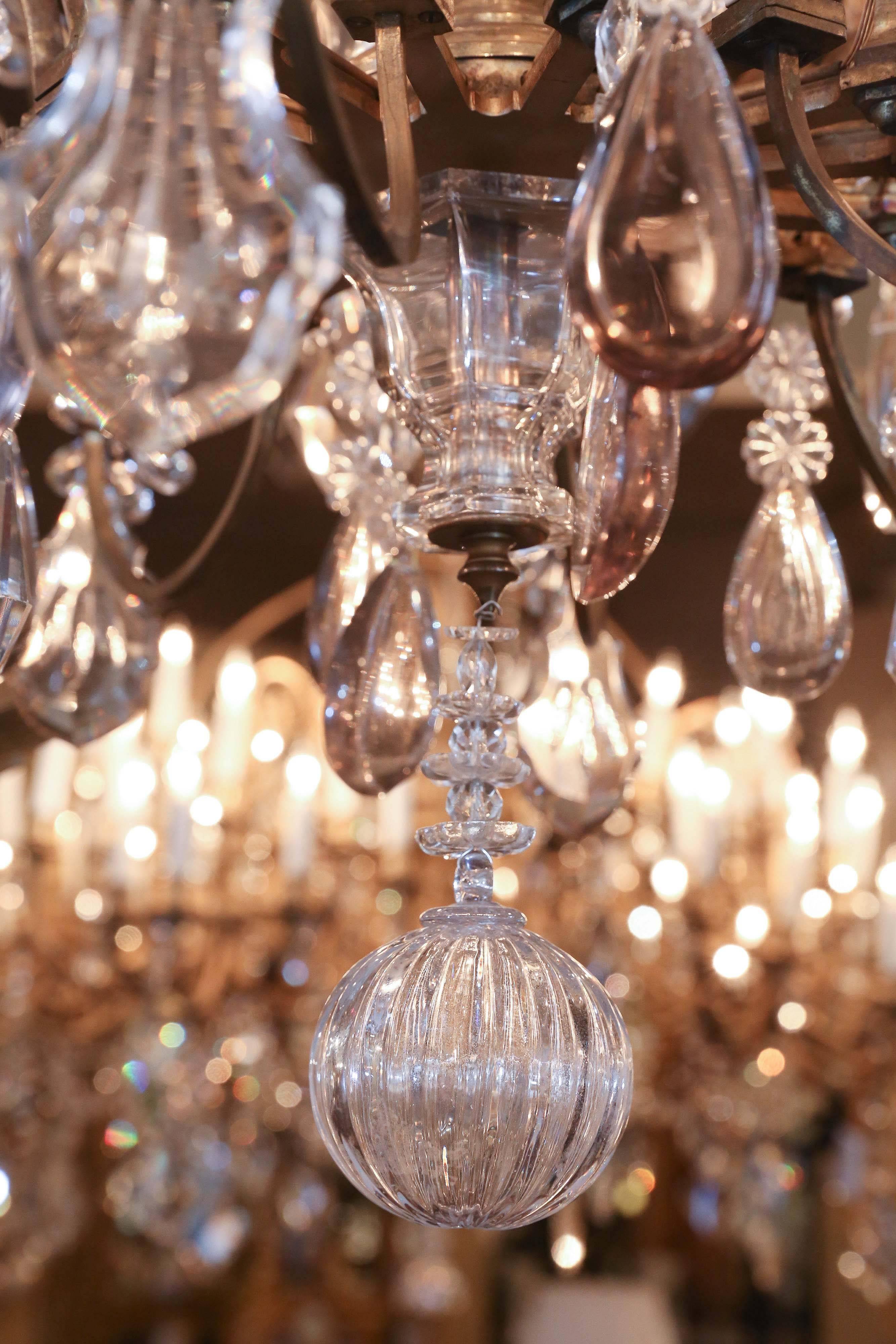 Elegant antique Baccarat chandelier with twenty eight lights. The scale is very grand with large opulent crystals 
 and tall spires. It has a mix of clear crystal with some crystal in 
Very pale lavender. The metal is a soft gilt bronze patina. The