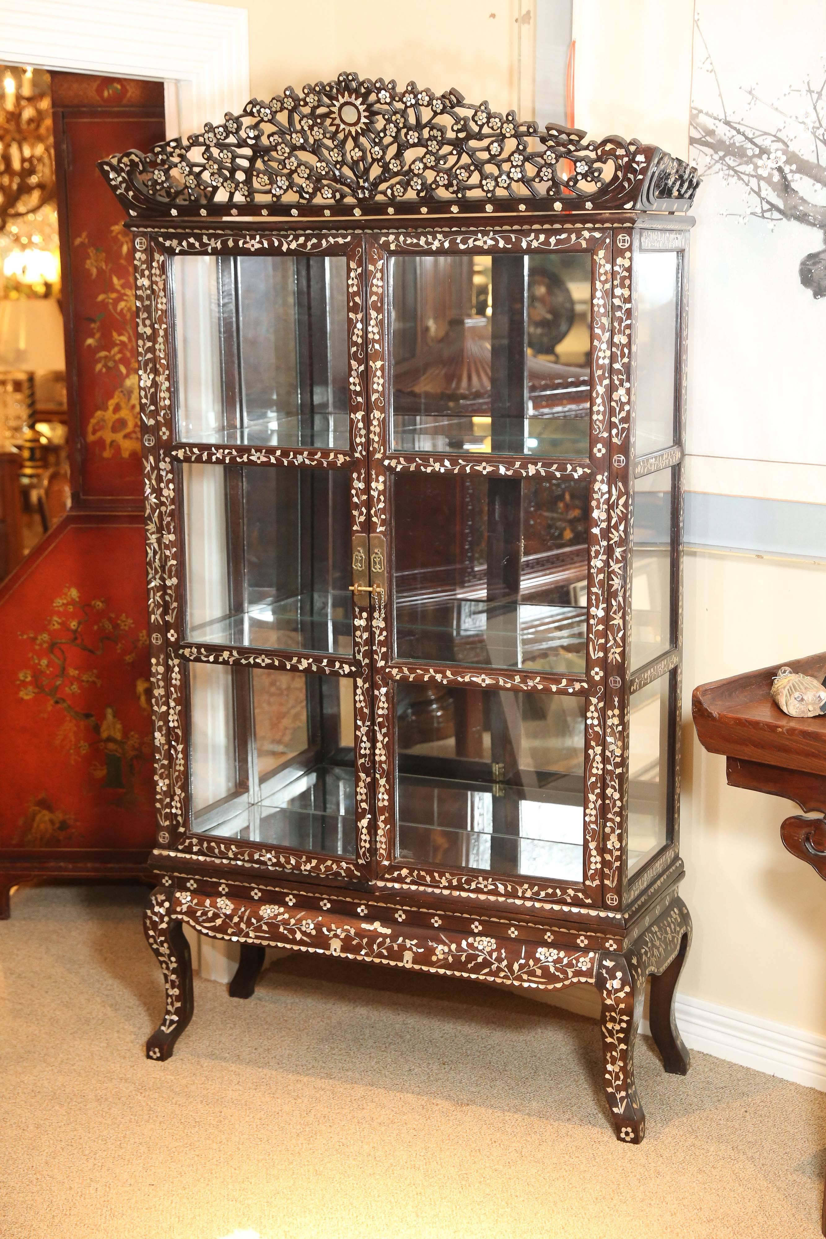 Vitrine en bois ébénisé avec incrustation de motifs en nacre. 
Il est doté de deux étagères en verre et d'un dos en miroir avec verre
Côtés. L'incrustation est exquise et le tout est en excellent état 
  