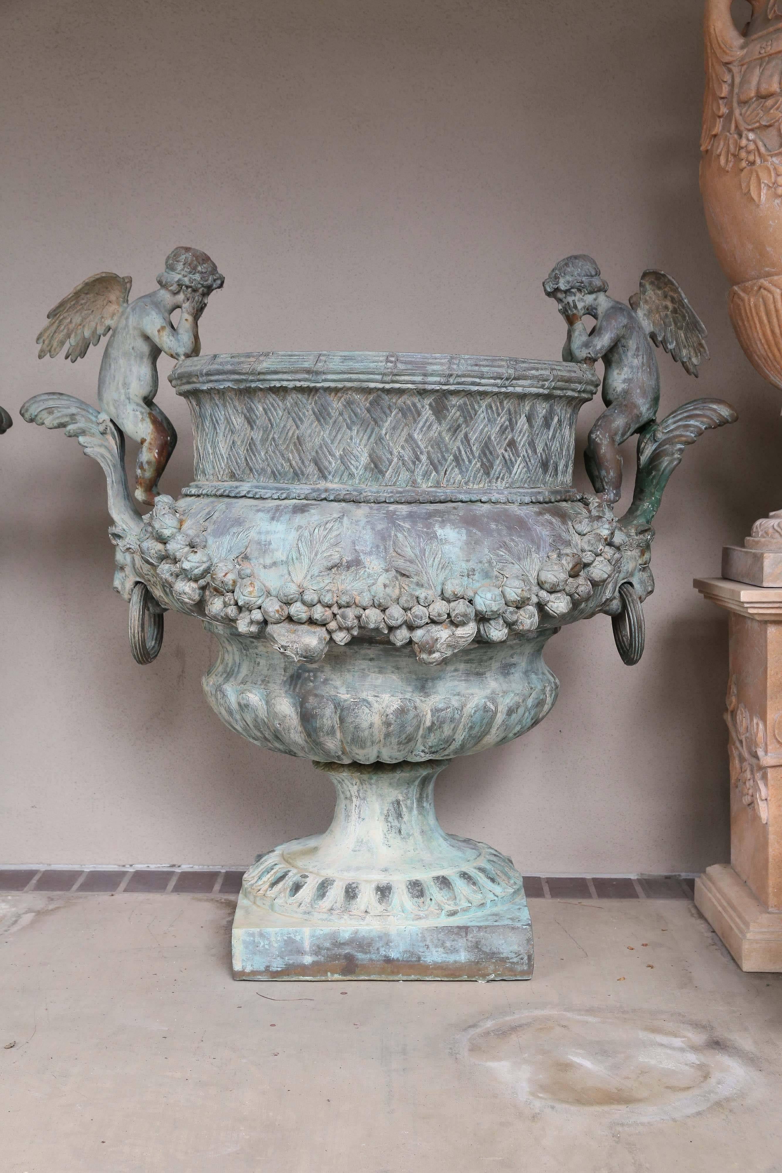 Grand scale planters made of bronze in a verde patina. Winged angels 
Sit along each side facing inward. A foliate garland drapes the main body
of the planters. Vintage with just the right amount of aging.