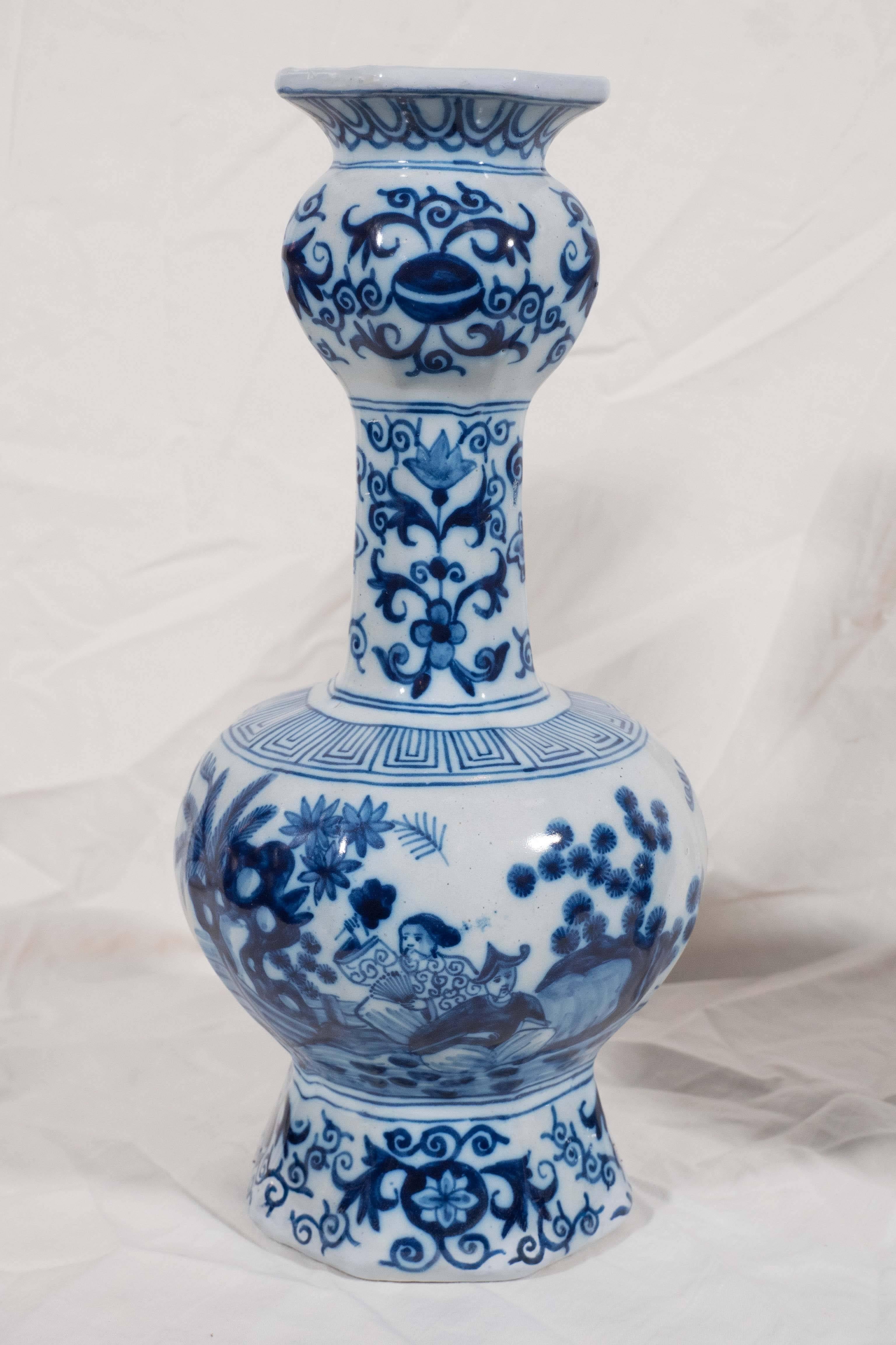 A pair of Dutch delft blue and white vases decorated with a beautiful chinoiserie garden scene with Mandarins, decorations of scrolling vines, and geometric designs.