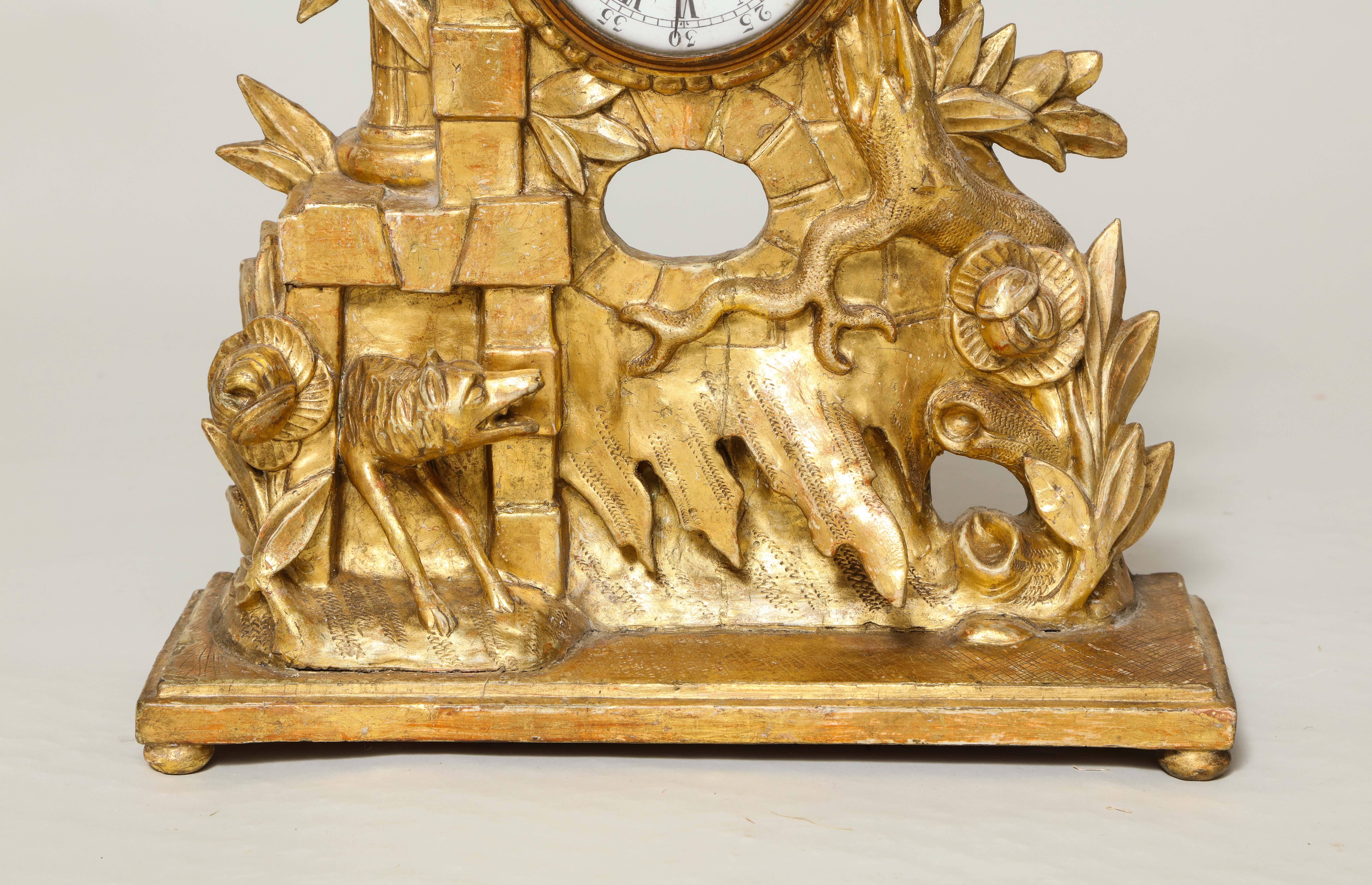 Fine 18th century rococo carved and giltwood shelf clock, the crest with stork holding a bone in his beak pearched on a romantic castle ruin with carved foliate decoration, vines and trees, the platform with wolf emerging from a quoin embellished