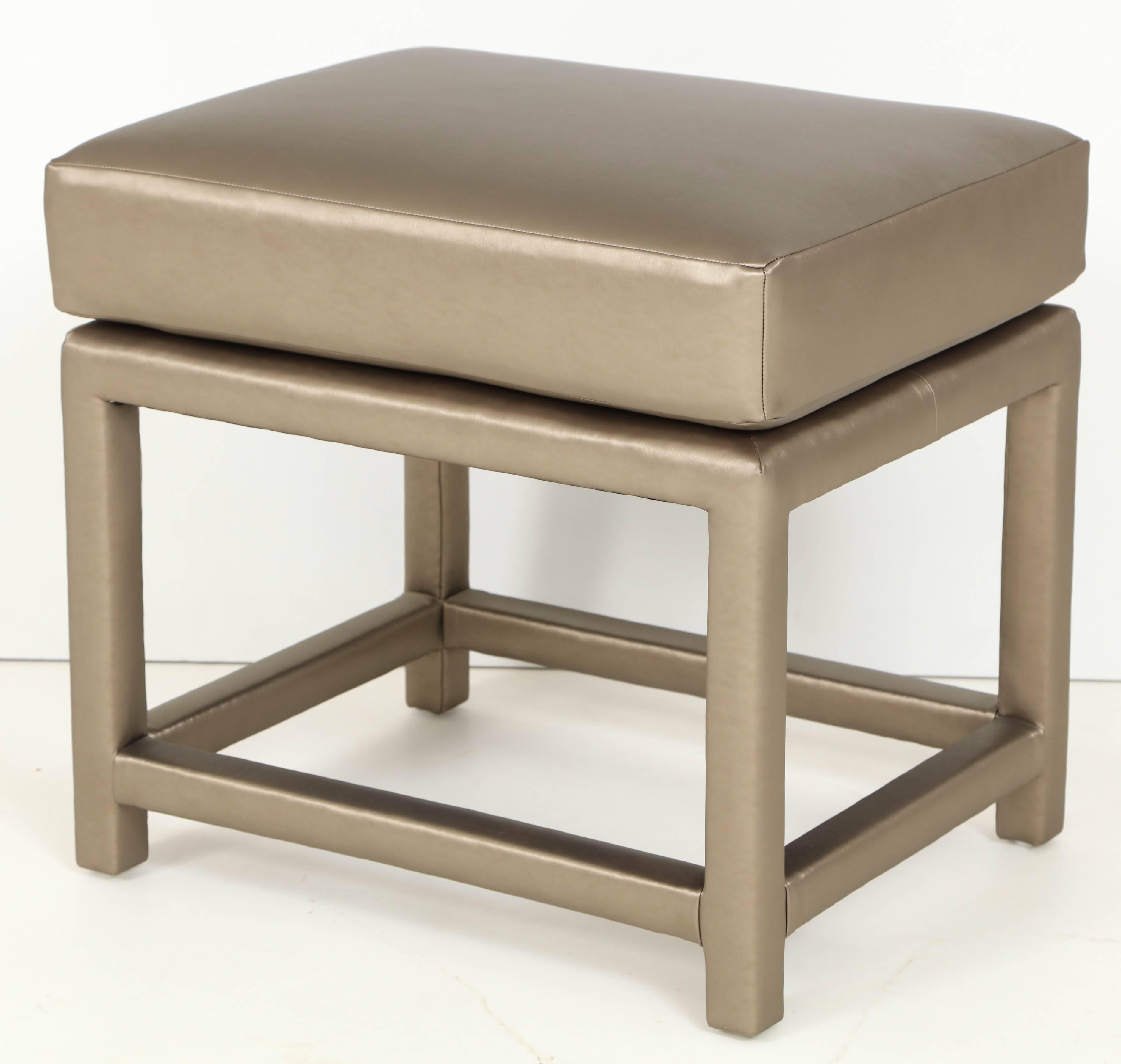 Pair of bronze metallic upholstered ottomans designed by Milo Baughman. Ottomans feature new bronze upholstered frames with attached cushions.