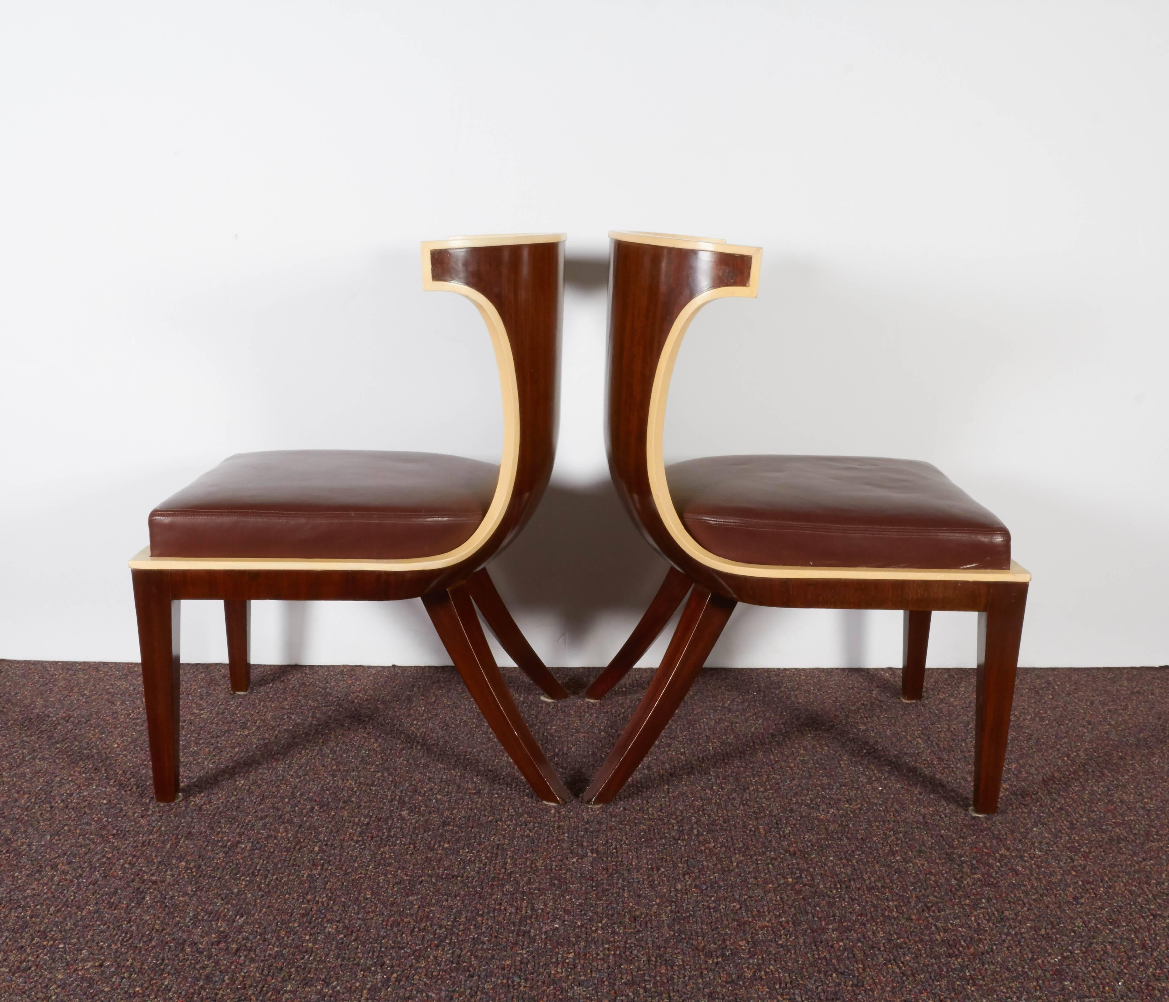 A pair of French Art Deco gondola side chairs by designer Ernest Boiceau (Swiss, 1881-1950), produced circa 1925, each with curved back in mahogany, painted ivory to the front and raised on saber legs, including leather seats. These chairs remain in