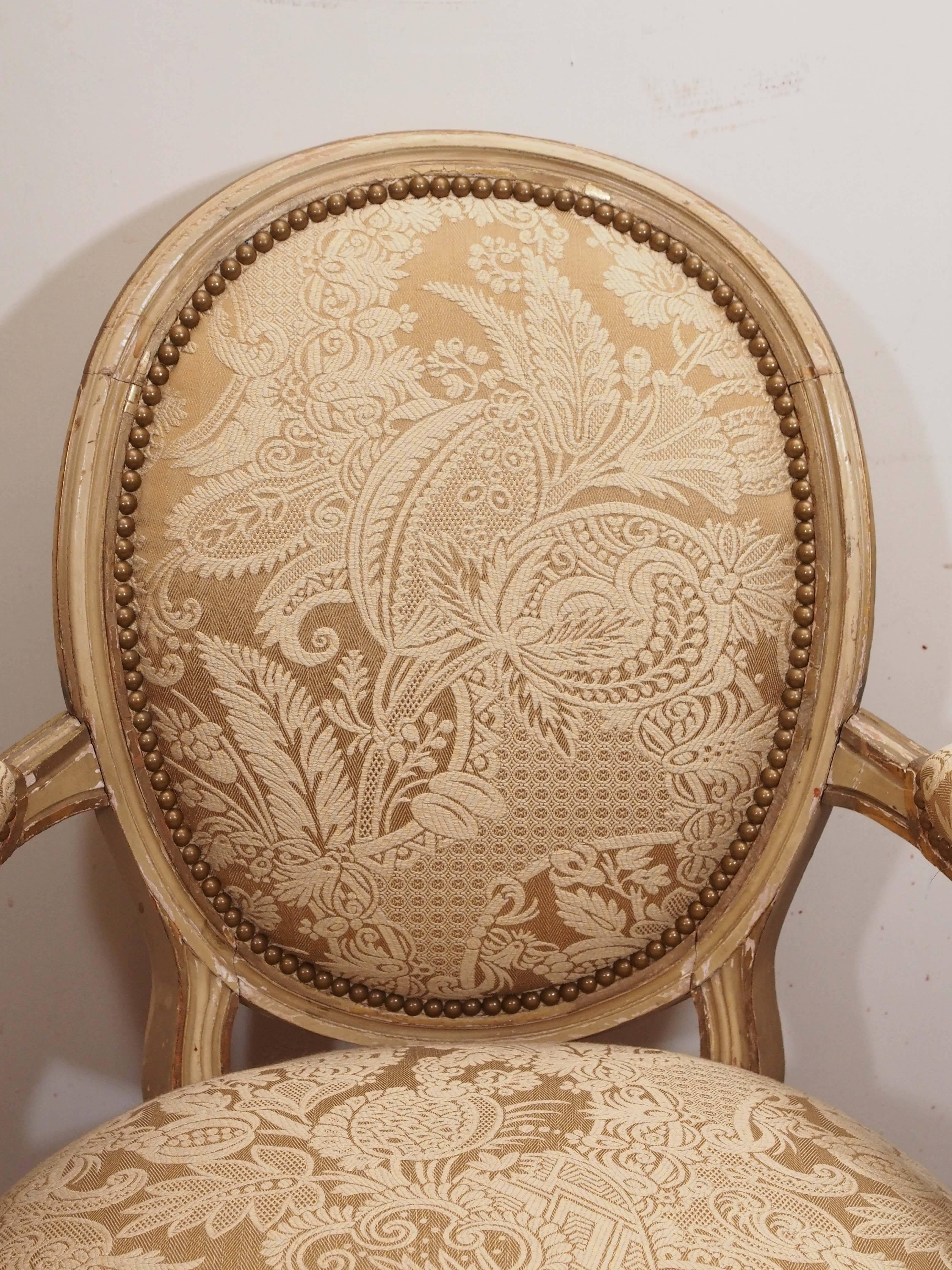 Pair of period Louis XVI oval backed armchairs with pegged construction and parcel gilt finish.
