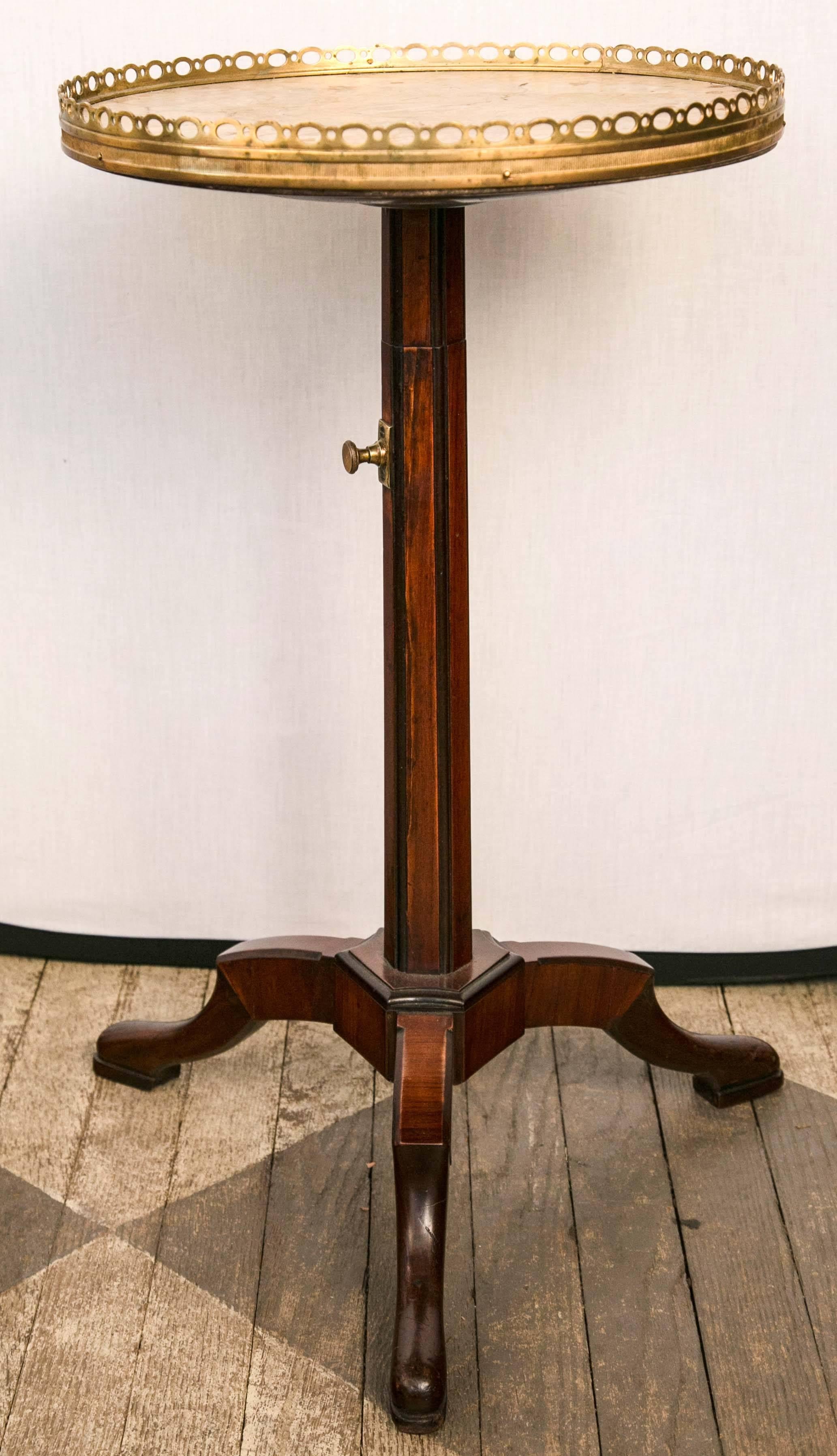 This very unusual French petit gueridon has a center column which telescopes up to a maximum height of 33 inches. A brass fitting allows for many different height adjustments with the holes drilled into the mechanism.
There is a brass gallery