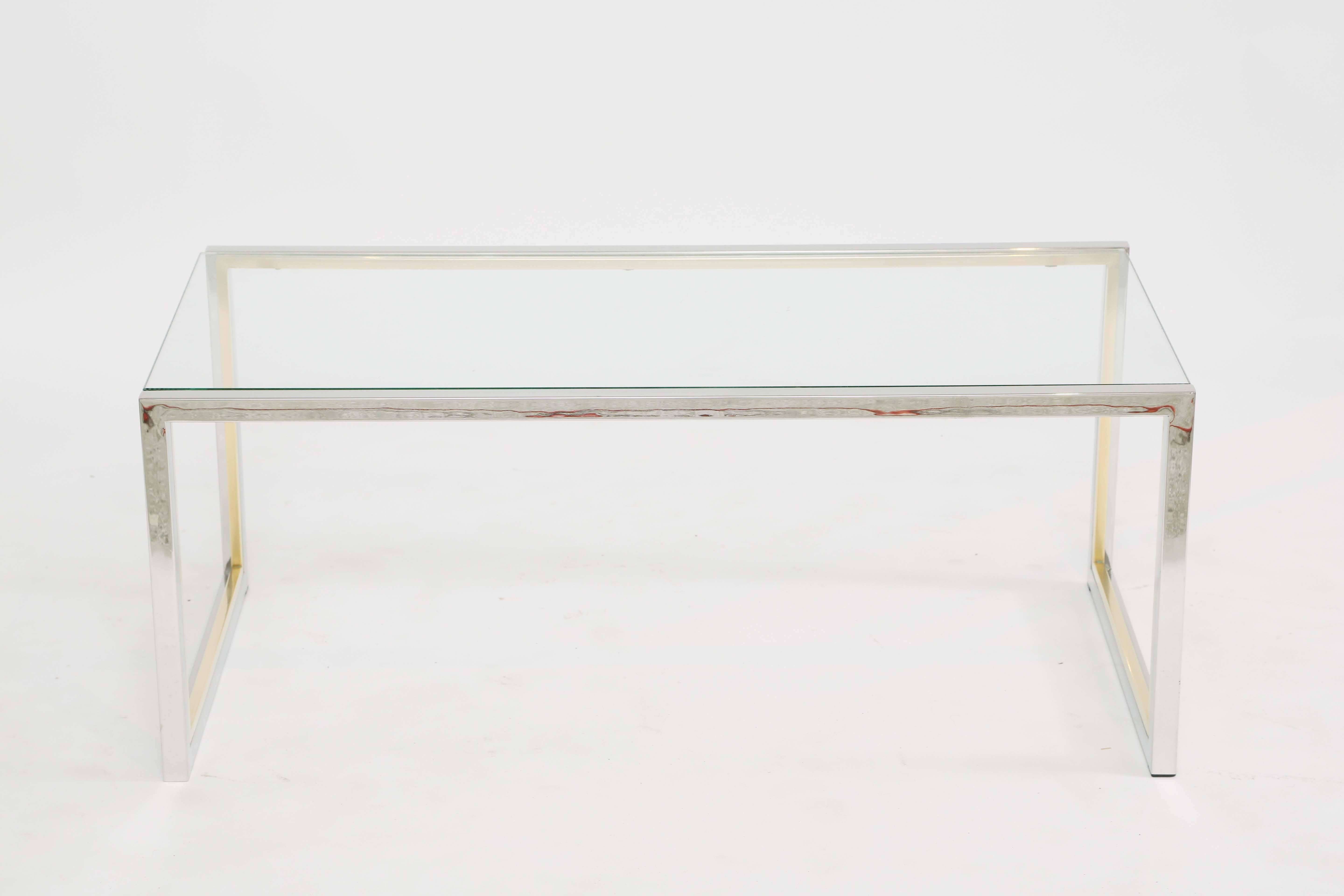 Table basse, en chrome et laiton, avec un plateau rectangulaire en verre, sur une base à section carrée, à cadre ouvert.

Stock ID : D8674