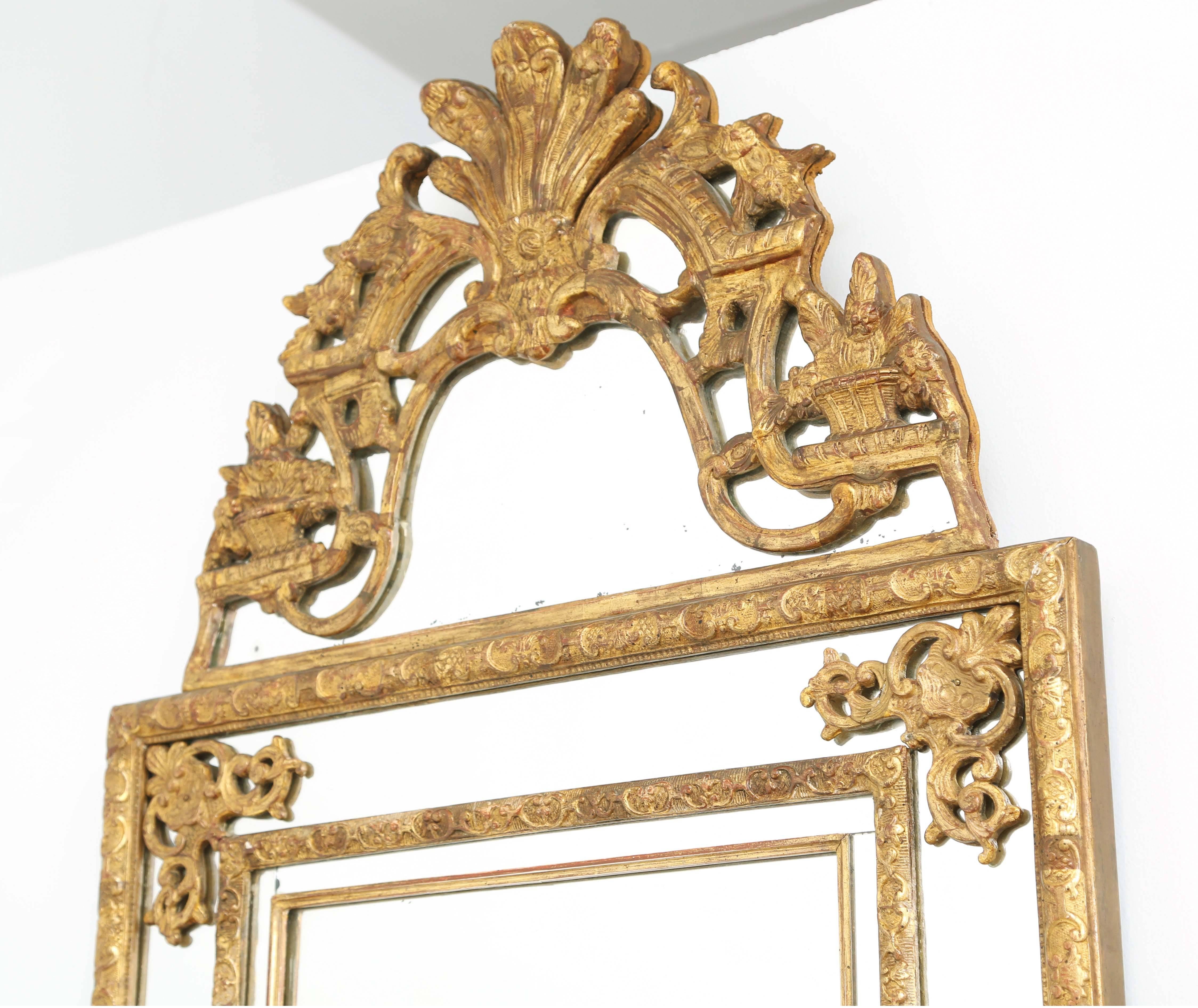 Wall mirror, of carved giltwood, its rectangular mirror plate, bordered in mirrored reliefs and gadrooned frame, each corner adorned with scrollwork, surmounted by pediment centered with palmette and flanked by foliate motifs.

Stock ID : D5256.
