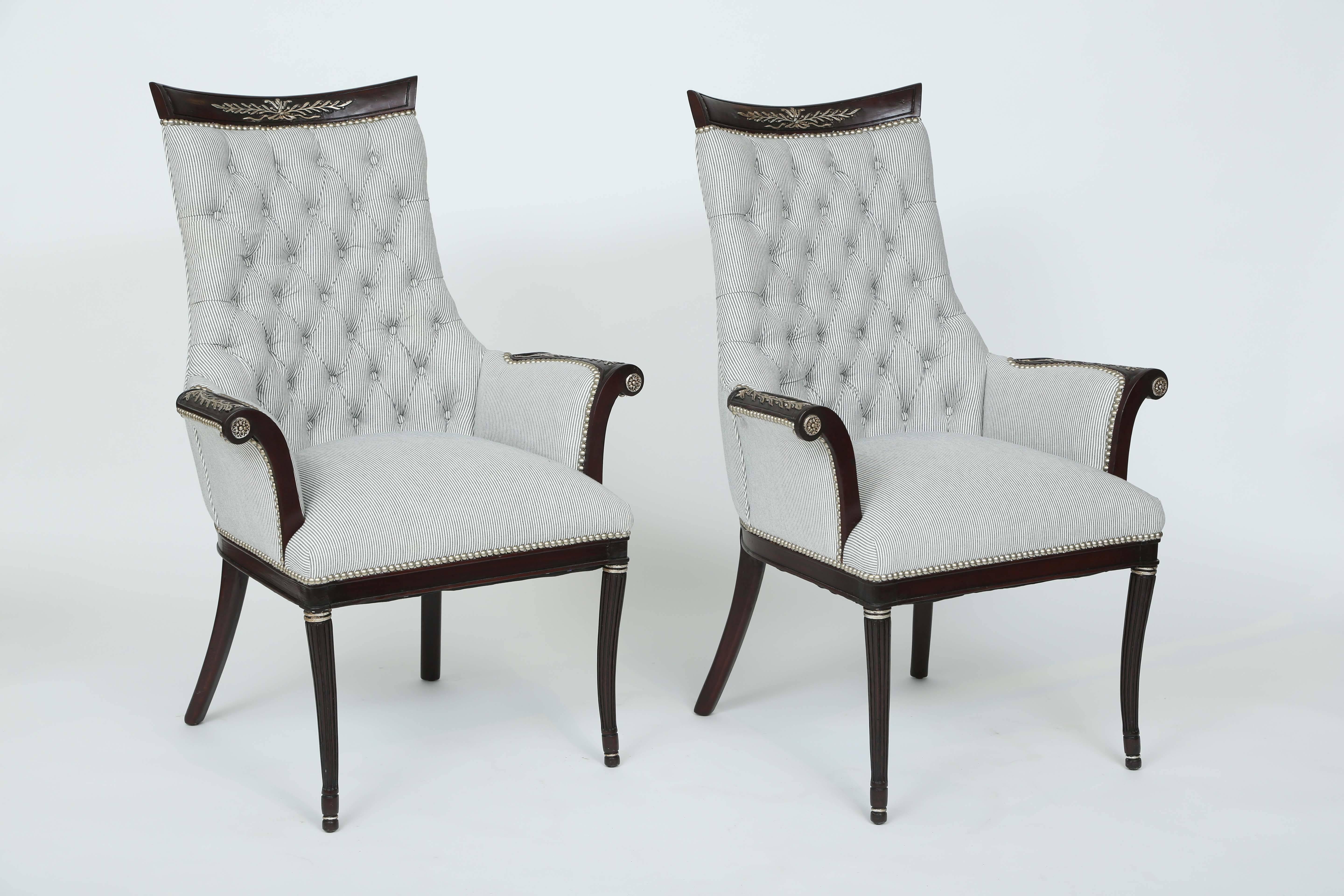 Pair of armchairs, having a black lacquered frame, each with a fielded bowed crestrail, centered by silver-gilt decoration of laureling, over shaped tufted backrest, out-scrolled upholstered arms with similar acanthine motifs on the elbow rests,