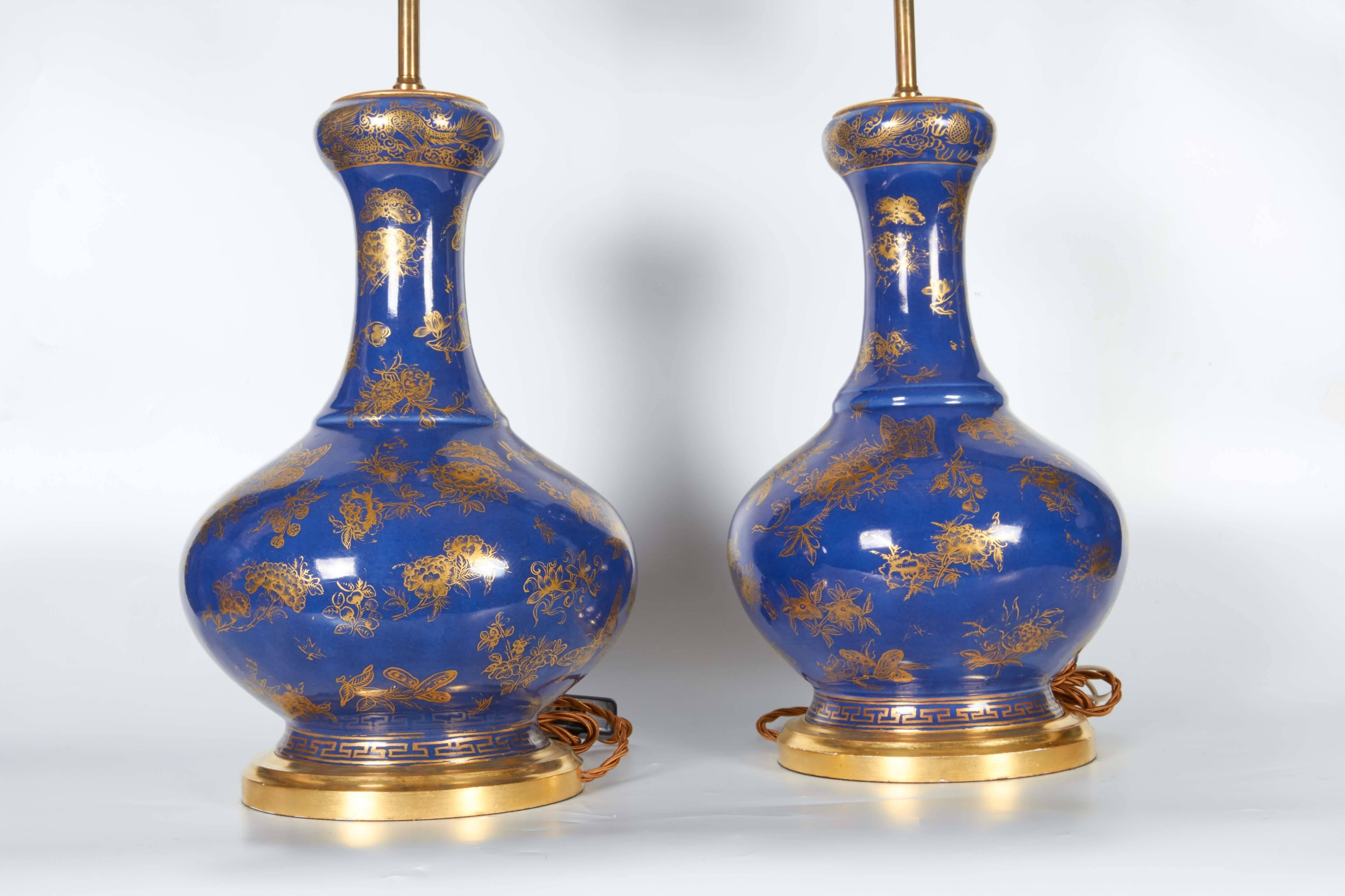 Pair of Chinese Blue Poudre porcelain and gilt hand-painted and decorated vases mounted as lamps, each hand-painted with flowers, Chinese dragons, butterflies and insects; on giltwood bases, the chinese Porcelain from the first half of the