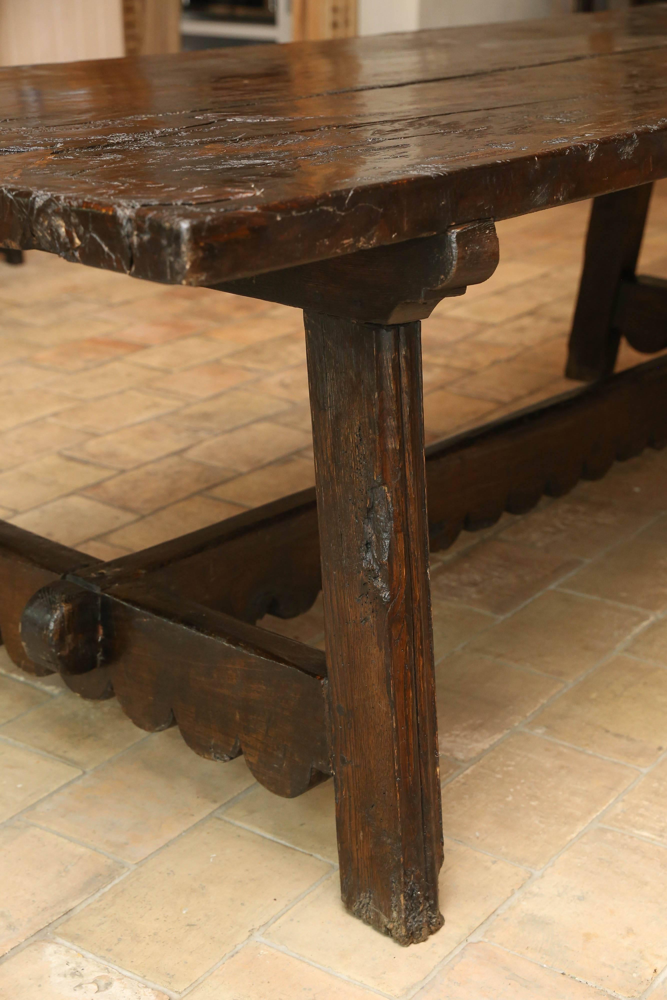18th century thick slab walnut table with a two board top. The base is a 100 years old. Table is from the Abuzzo region of Italy. Both the legs and the trestle have a hand-carved scallop detail a variation on the St. Antonio style.