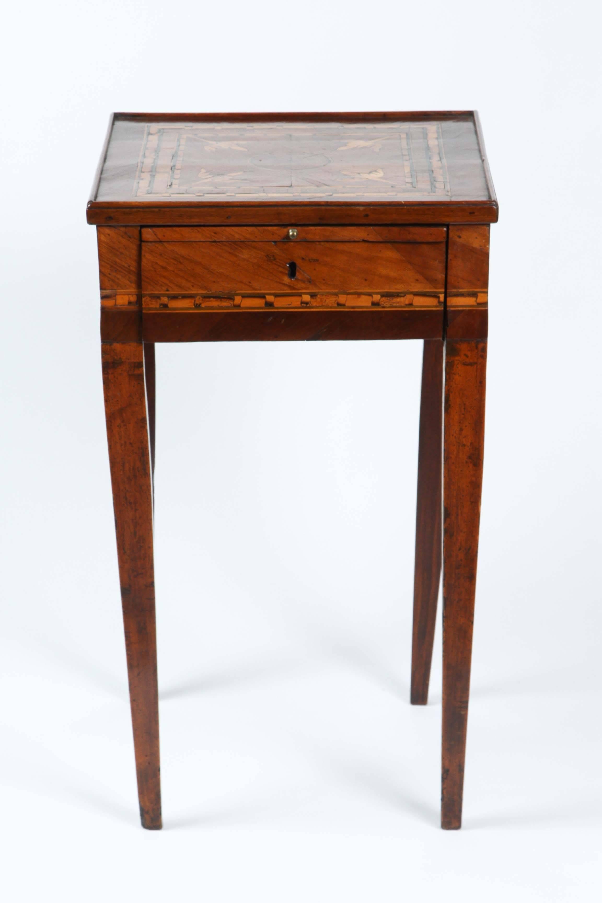 An unusual small Italian walnut table, with striking inlaid decoration, writing slide and drawer.