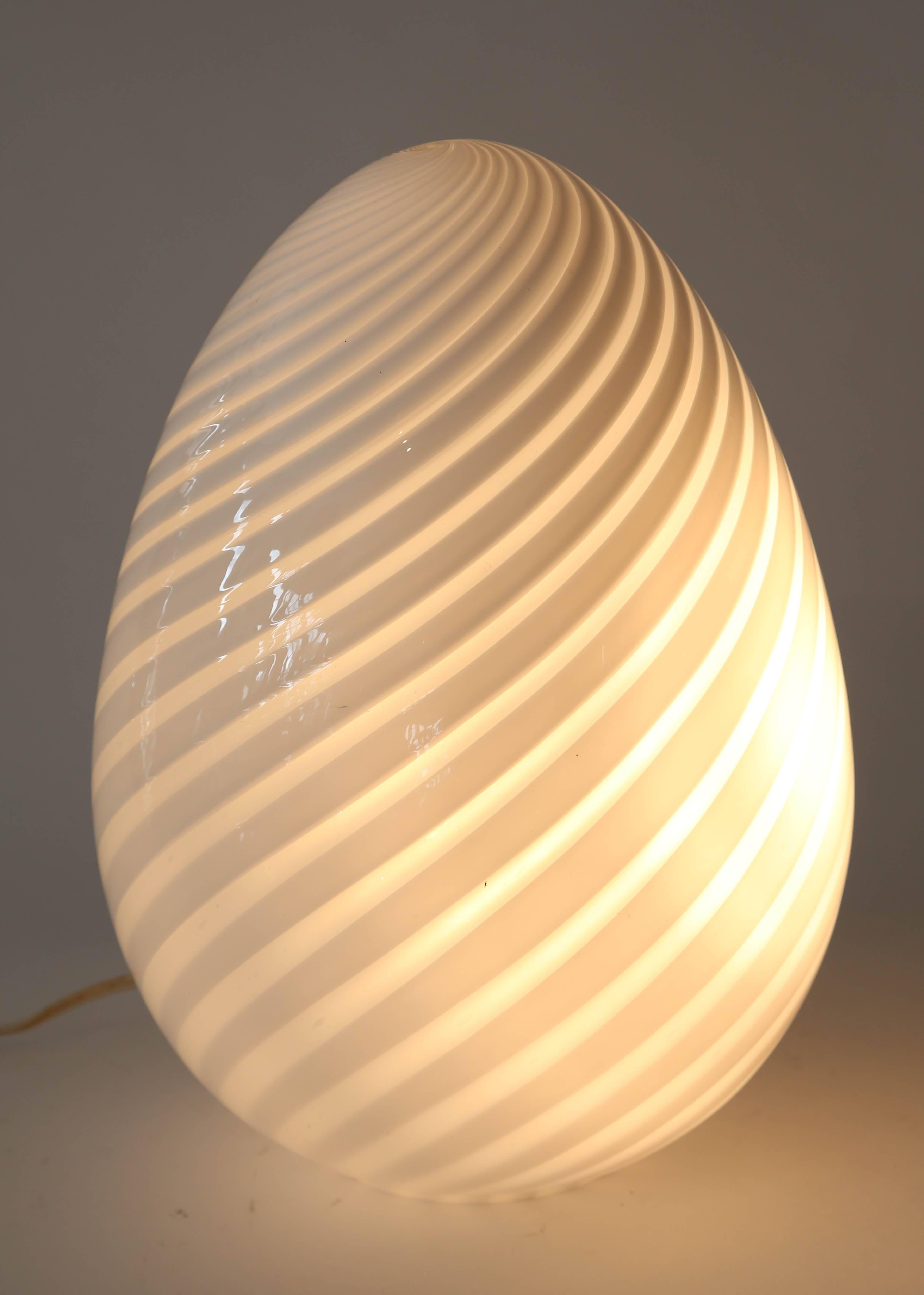 Stunning Mid-Century Modern Italian handblown Murano glass egg shape table lamp made by Vetri in the style of Venini. This lamp has a clear and white glass spiral pattern that casts a wonderful glow when lit. It stands 15