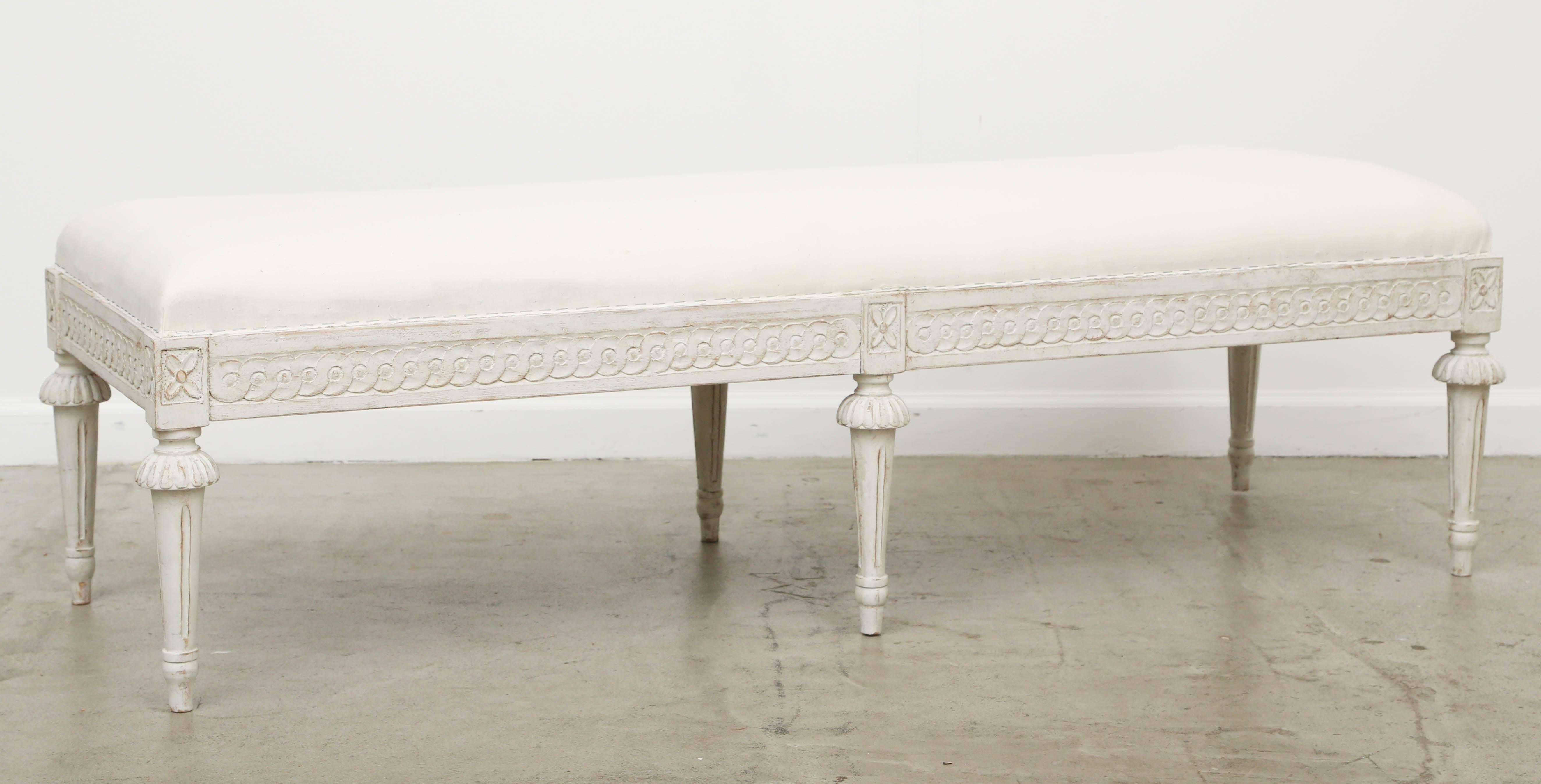 Antique Swedish Gustavian Style long painted bench, mid-19th century. 
Six-leg bench has carved interlocking circular border on apron and rosets above each tapered fluted leg. Swedish white distressed paint finish. 

Measures: 59.00 in W x 19.75 in