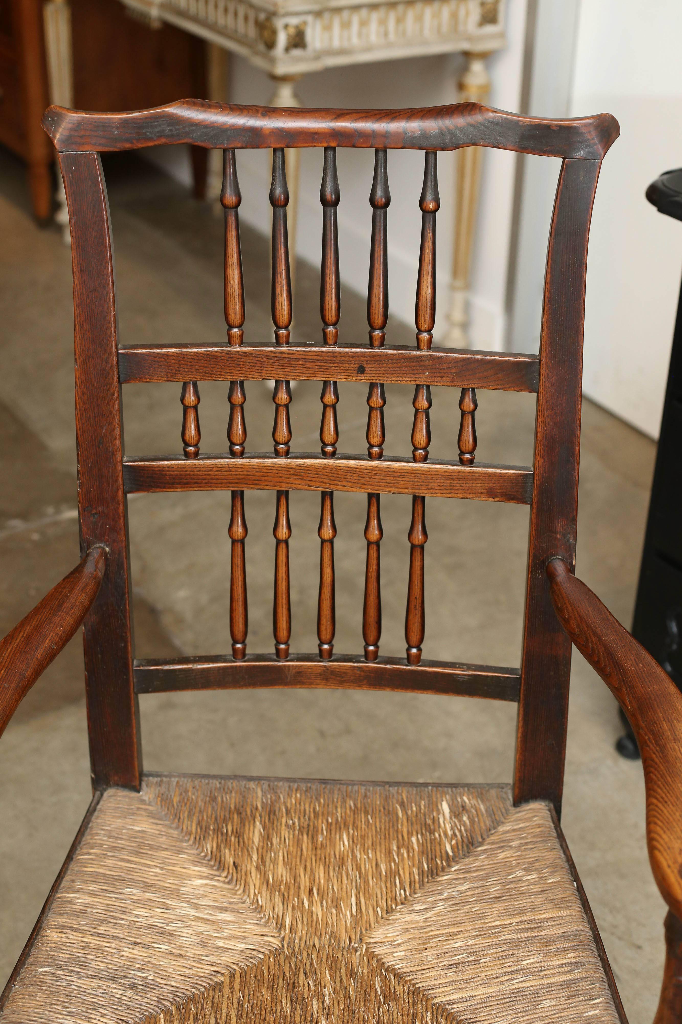 A charming and lovely example of an ash and rush seated Cheshire country chair. This large elbow chair having superb color and patina throughout. With a decorative spindle back and outswept shaped arms adjoined to the seat with turned uprights,