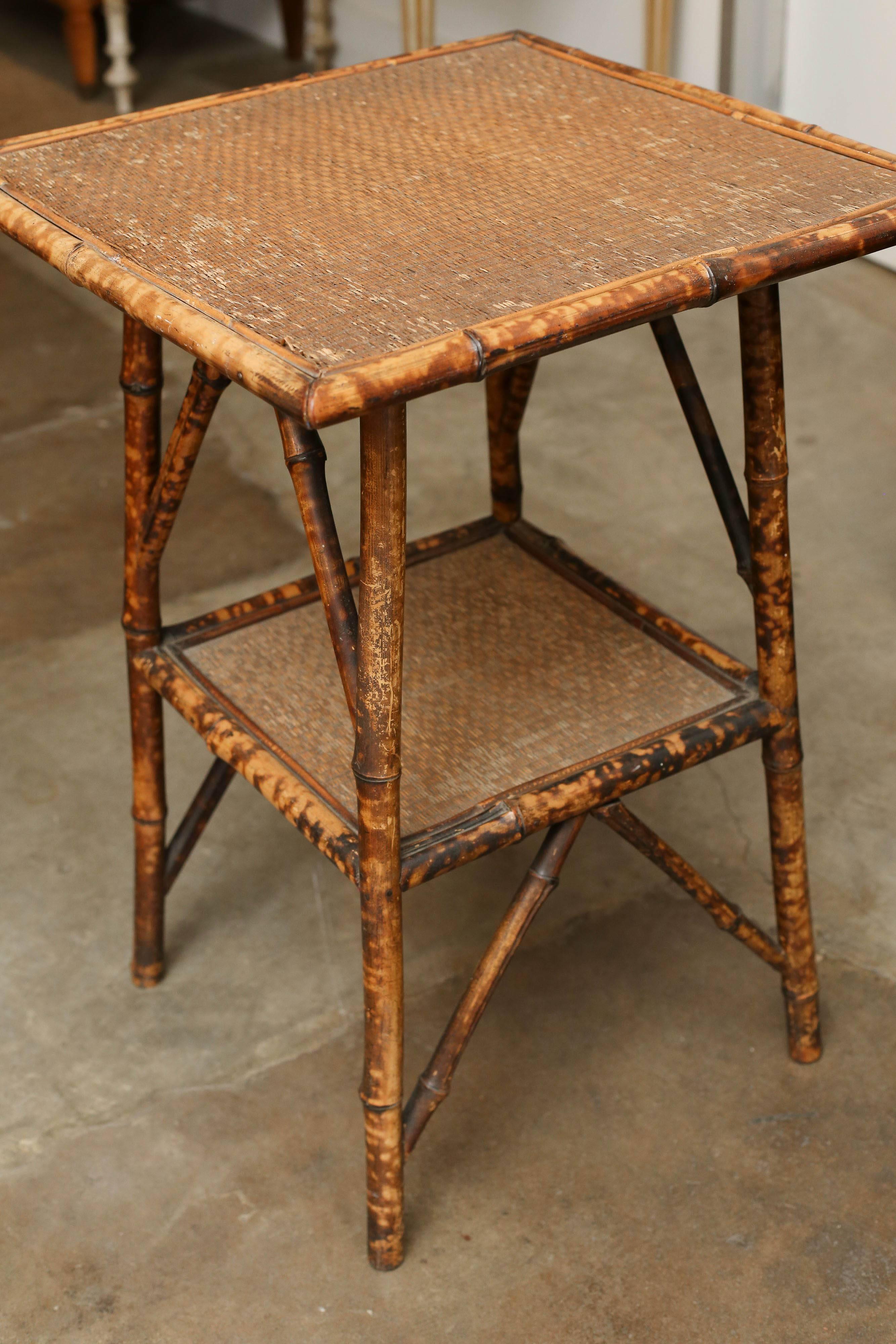 19th century scorched bamboo side table with a bottom shelf on four legs supported by diagonal sketchers.