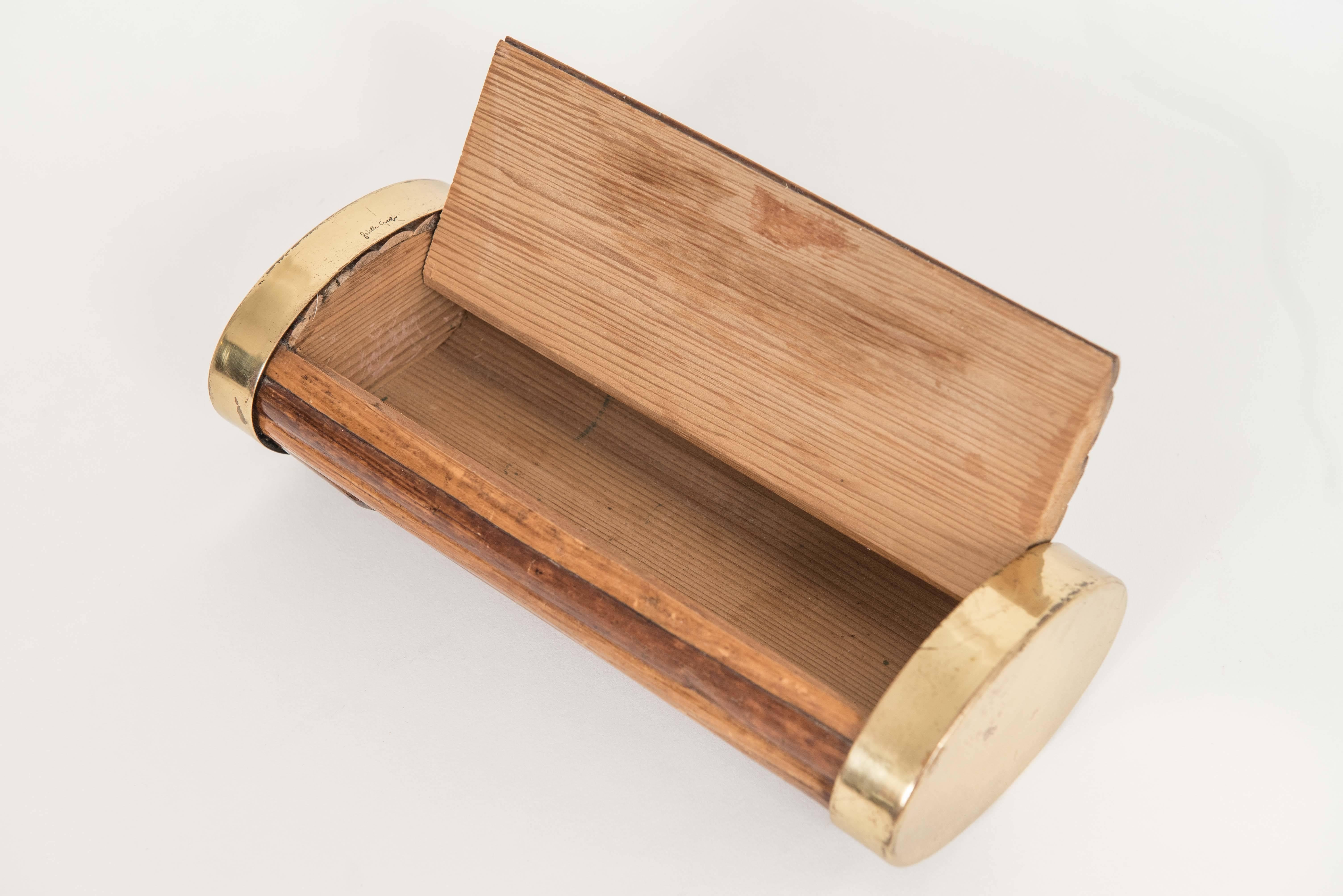 Oval section bamboo and brass box with applied shield at the center. Interior lined with cedar wood. Engraved signature.