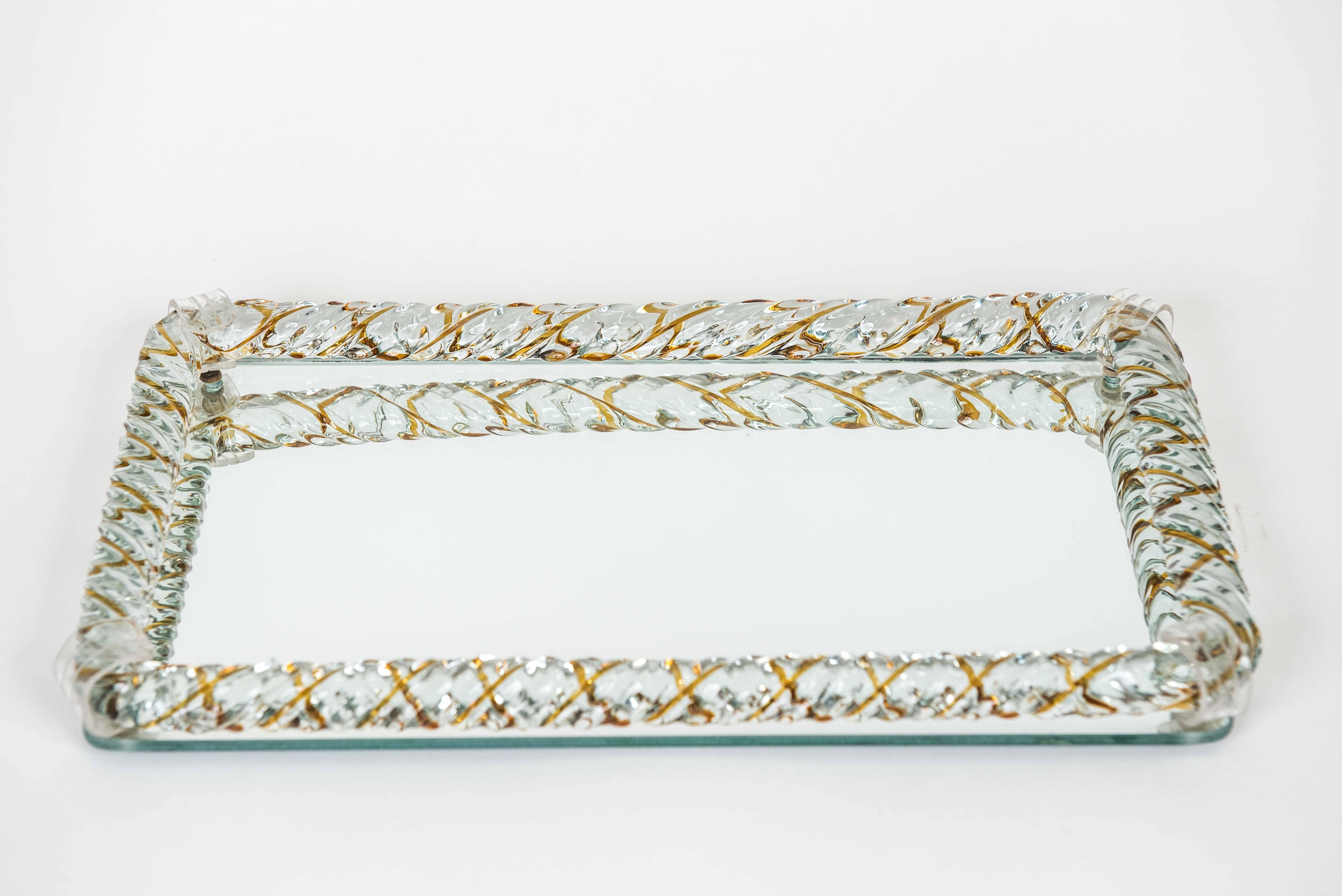This clean and glamourous Murano tray
with braided glass edge and acrylic clasps makes a nice gift for the holiday season. It is infused with an amber detail.