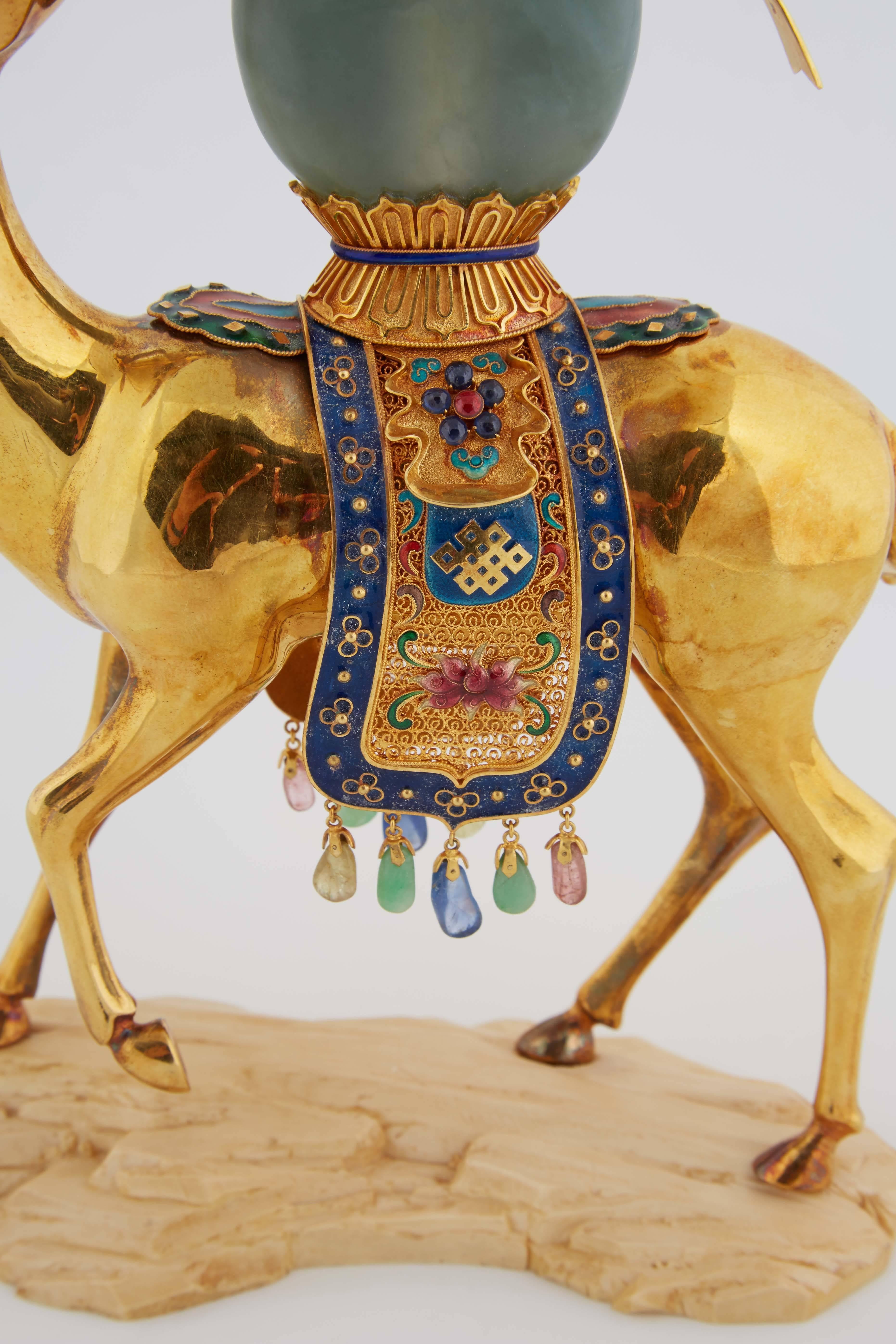 Chinese 18-karat solid gold enamel and precious stone deer with jade.

Marked 18-karat.

The deer with an enameled drape across its back and a jadeite snuff bottle on a resin rock-form base.

9